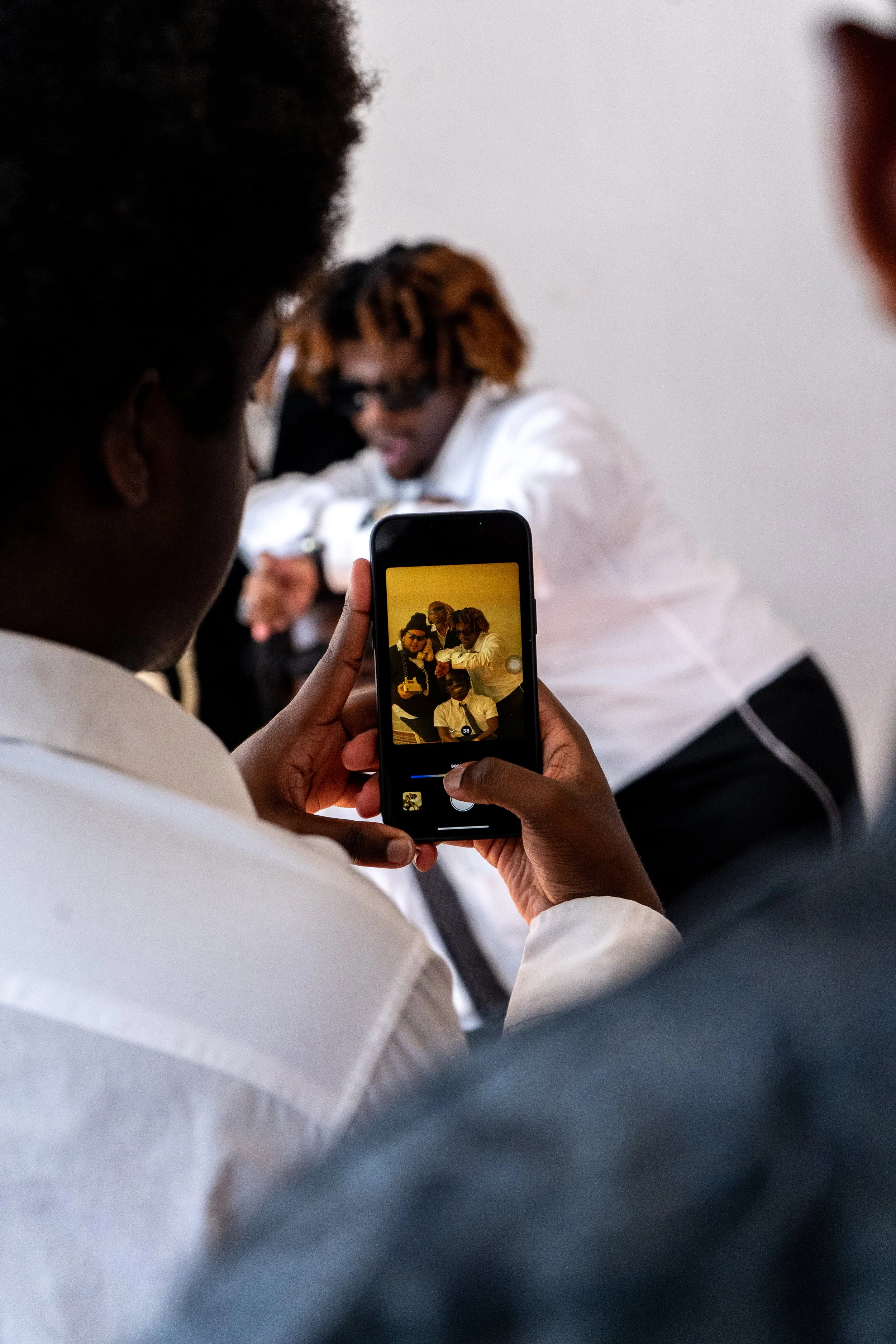 Person taking a photo of a group of people using a smartphone.
