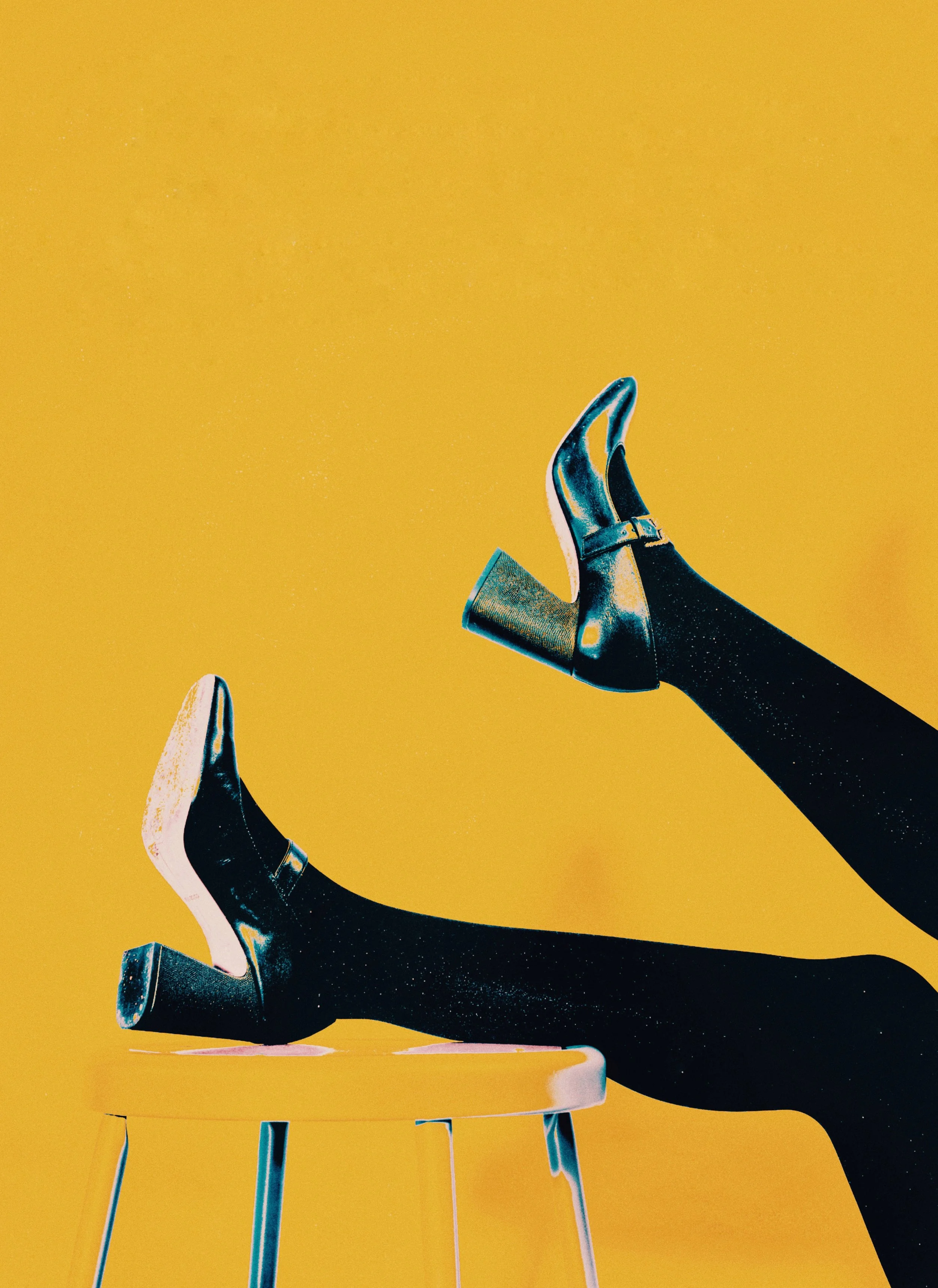 A person wearing black tights and black high-heeled boots with buckles, lying on a yellow stool with one leg raised in the air against a yellow background.