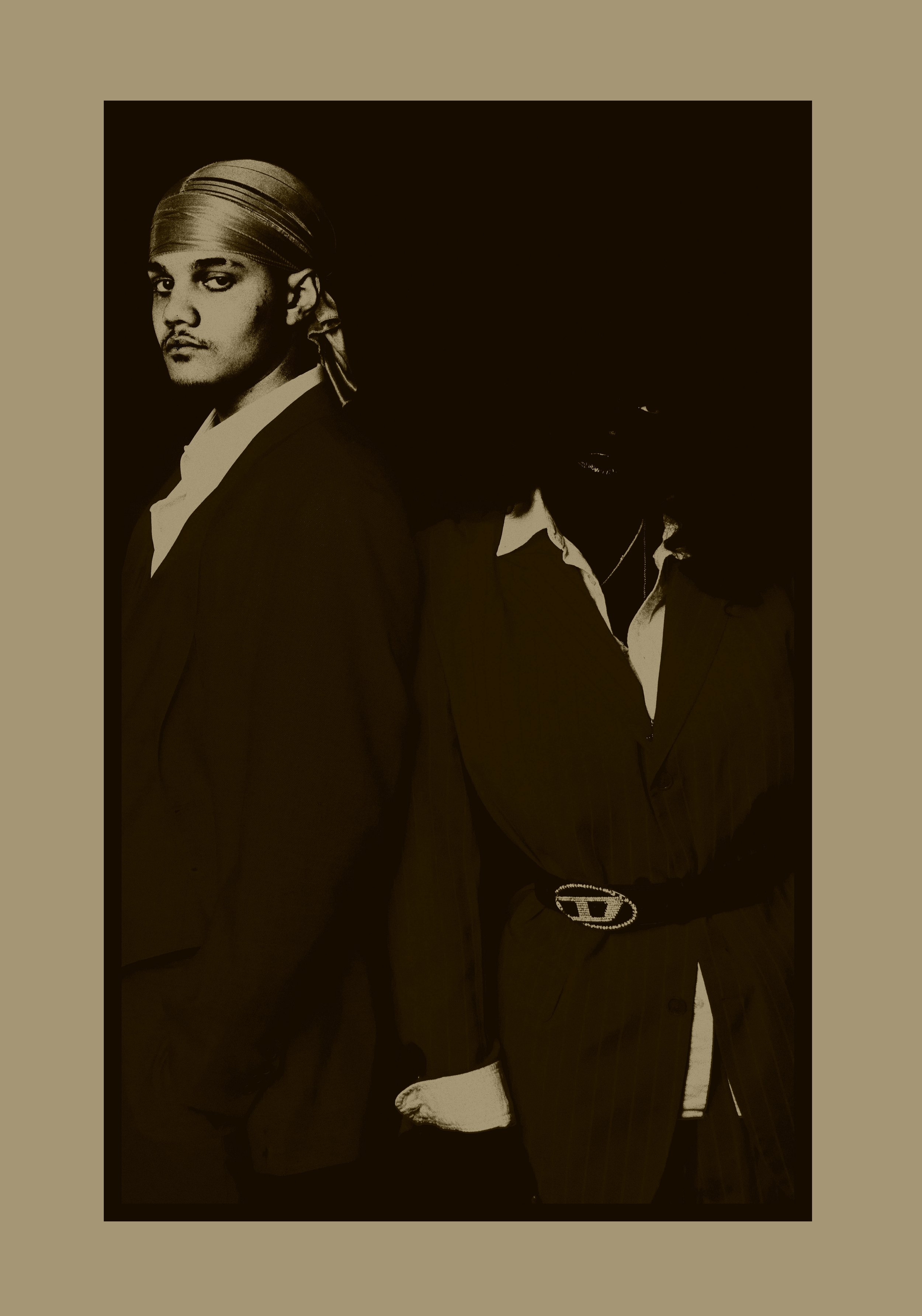 A black and white portrait of three people, with one man prominently in the foreground and two others partially visible behind him. The man in the foreground has a mustache, a head covering, and is wearing a suit with a belt visible.
