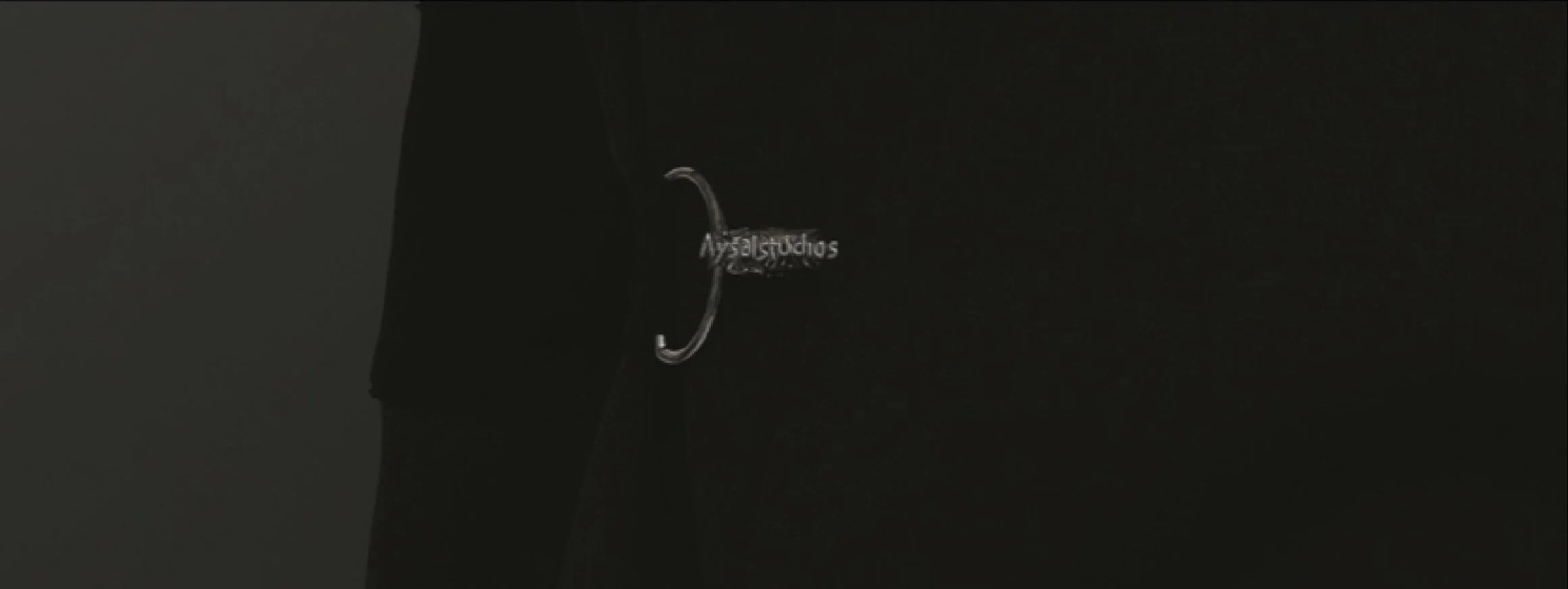 Close-up of a black fabric with a small, metallic tag that reads 'Aysalstudios' on it.