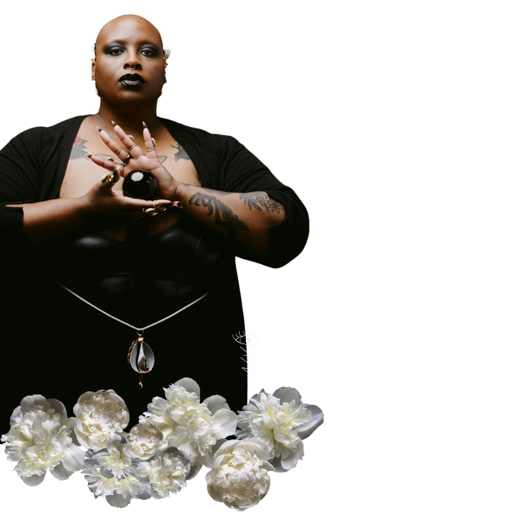 A human with dark makeup, tattoos, and a serious expression, holding a black sphere with both hands, standing against a black background, surrounded by white flowers at the bottom.