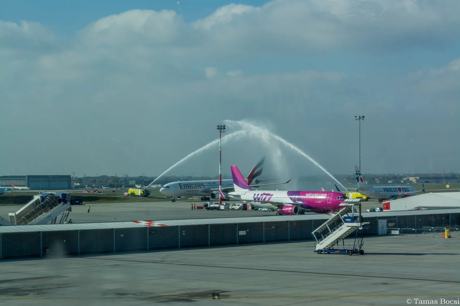 Airplanes on the tarmac at an airport, with water hoses spraying water over the aircraft in a celebratory water salute.
