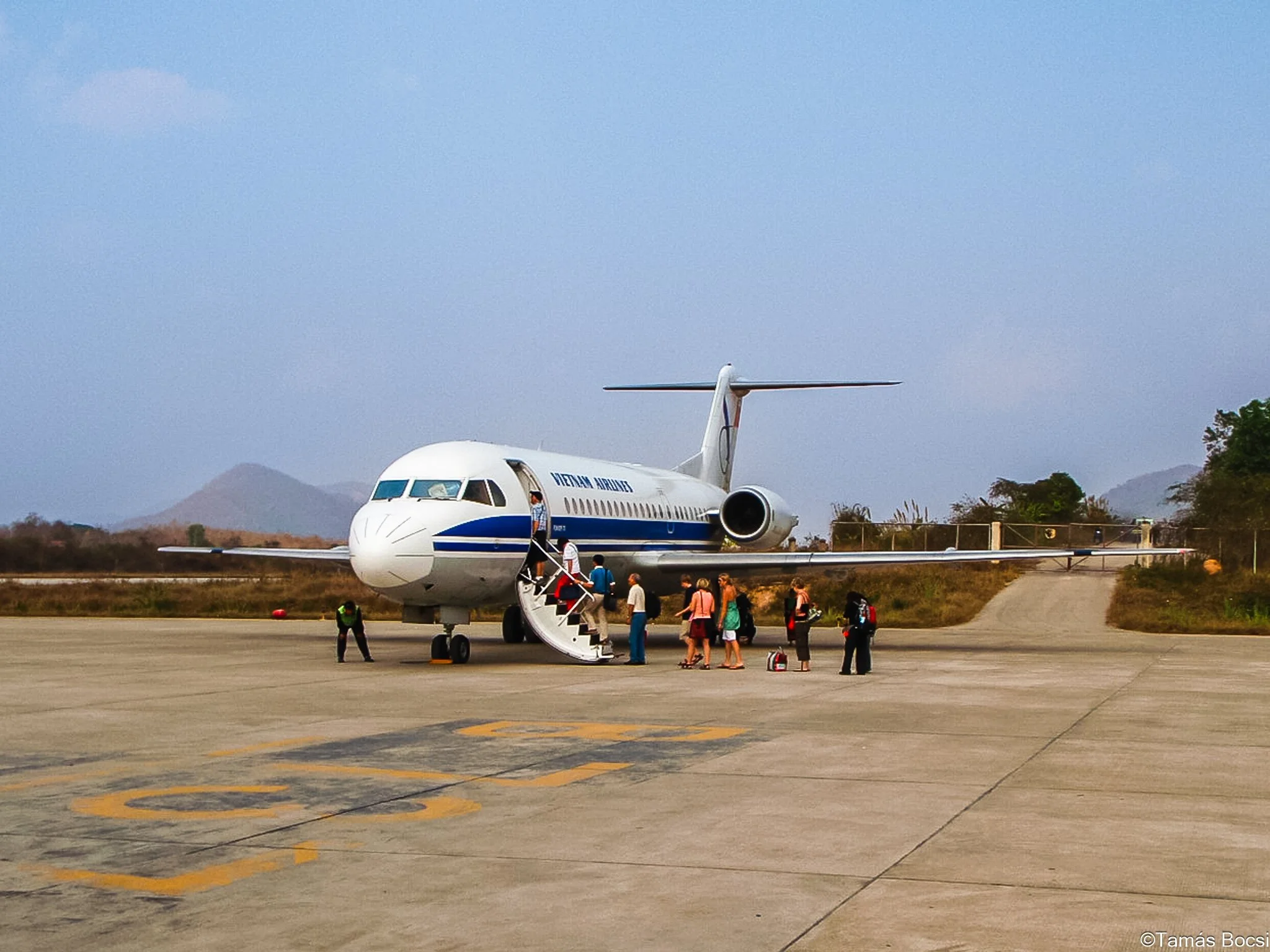 A group of passengers boarding a Vietnam Airlines airplane on the tarmac.
