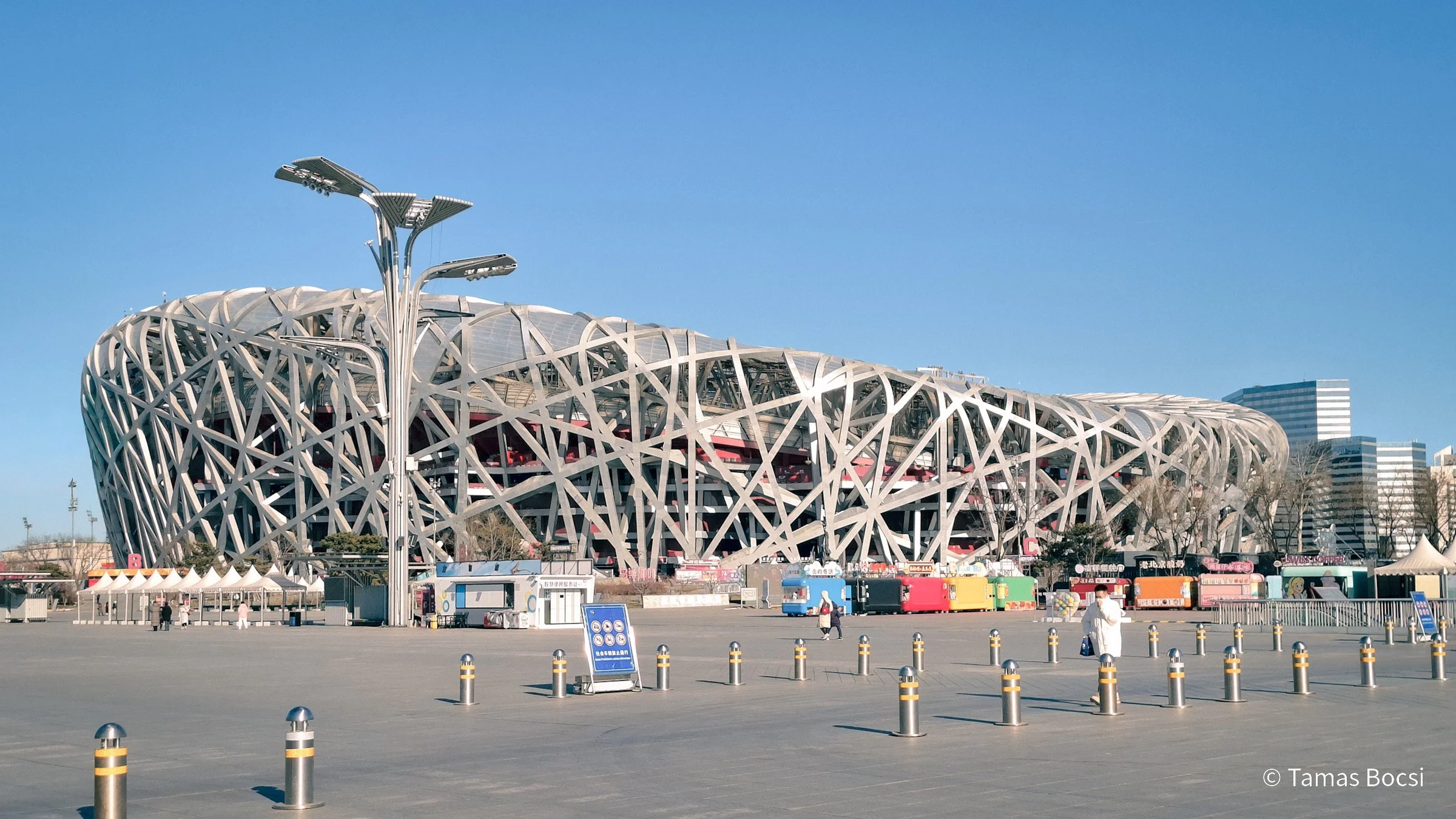Modern stadium with a futuristic design, metal lattice exterior, and a clear blue sky.