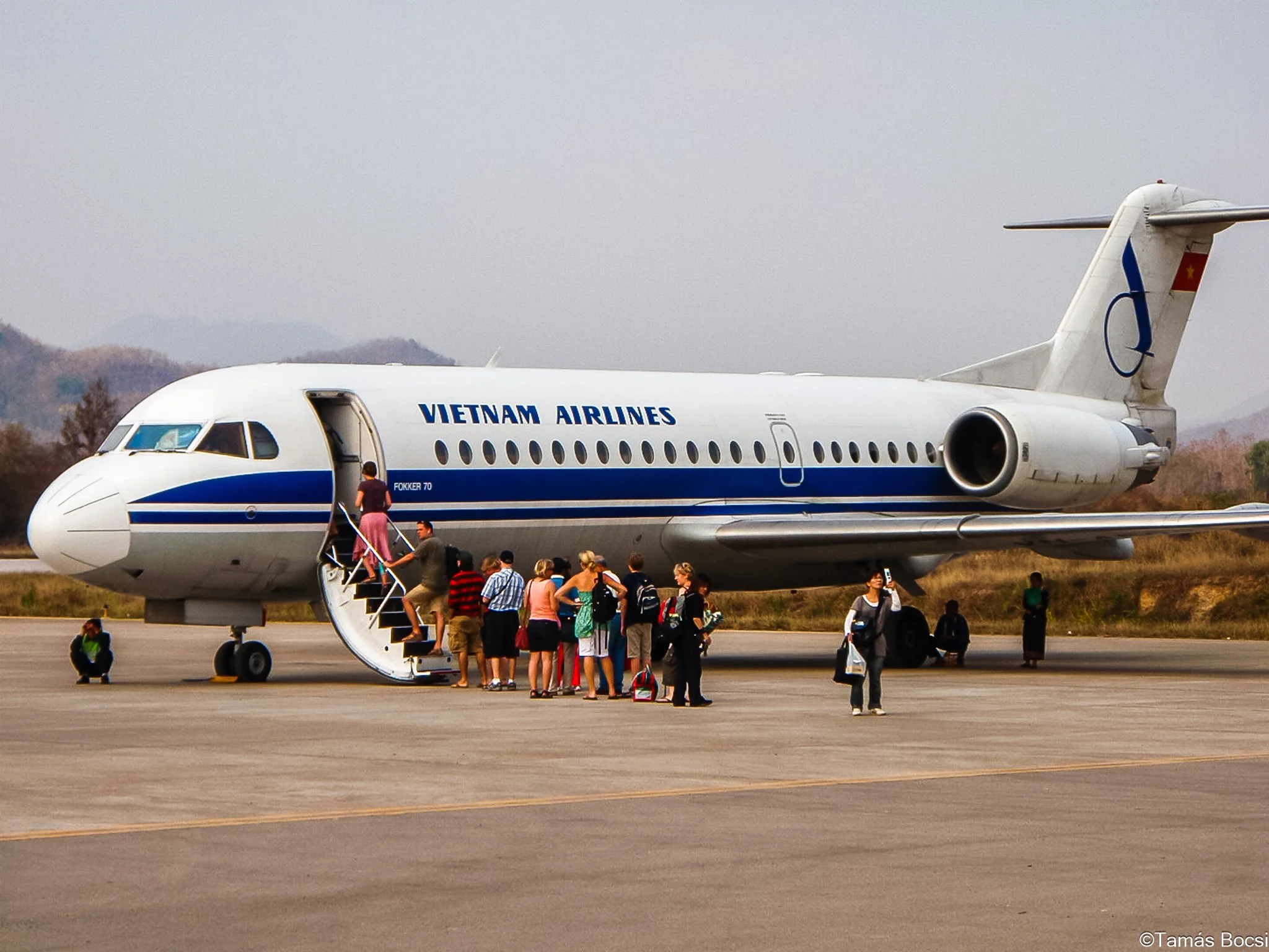 Passengers boarding a Vietnam Airlines airplane on the tarmac.