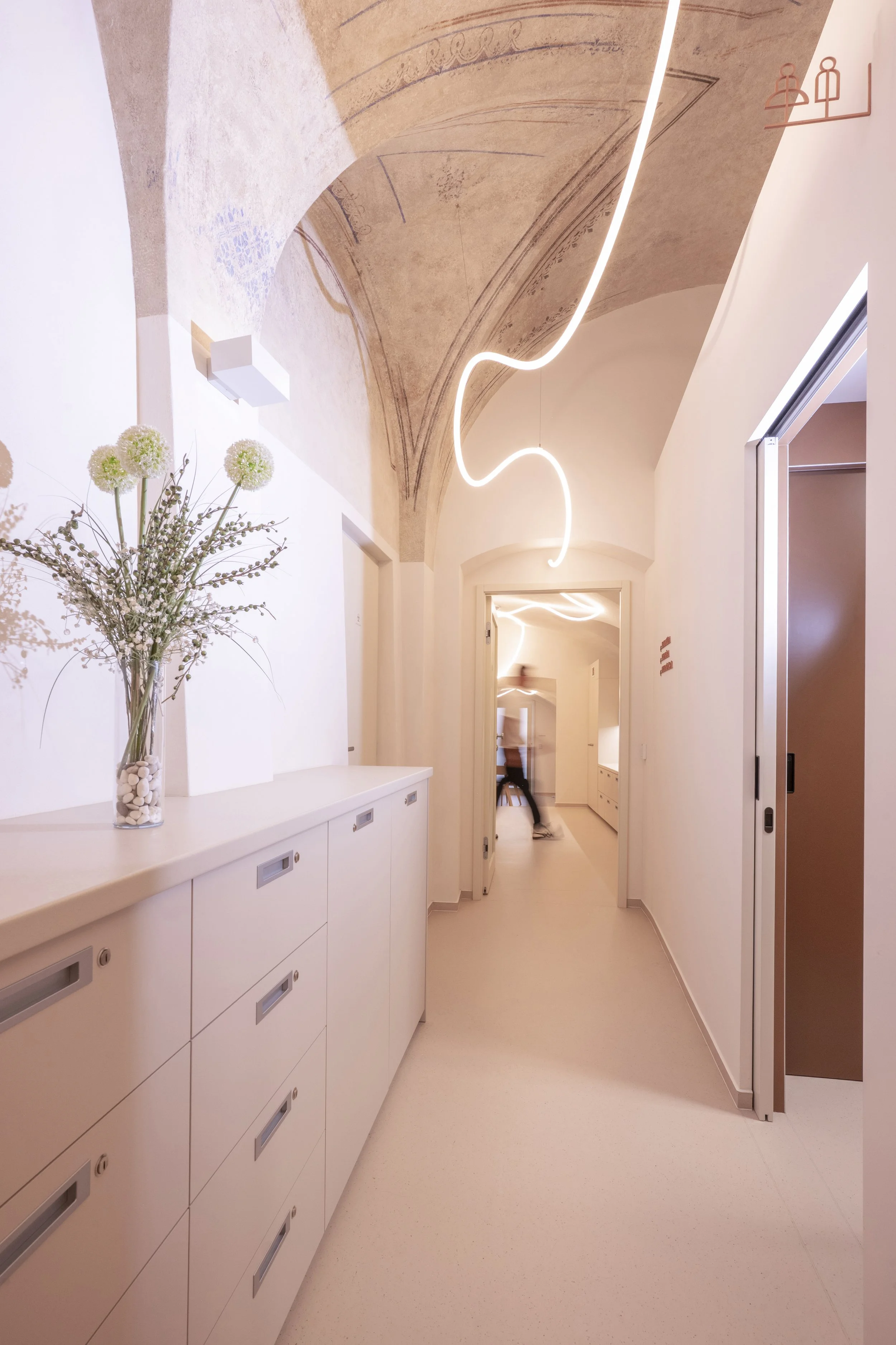 The clinic's hallway, featuring custom-made furniture and a light fixture beneath the historic vaulted ceiling