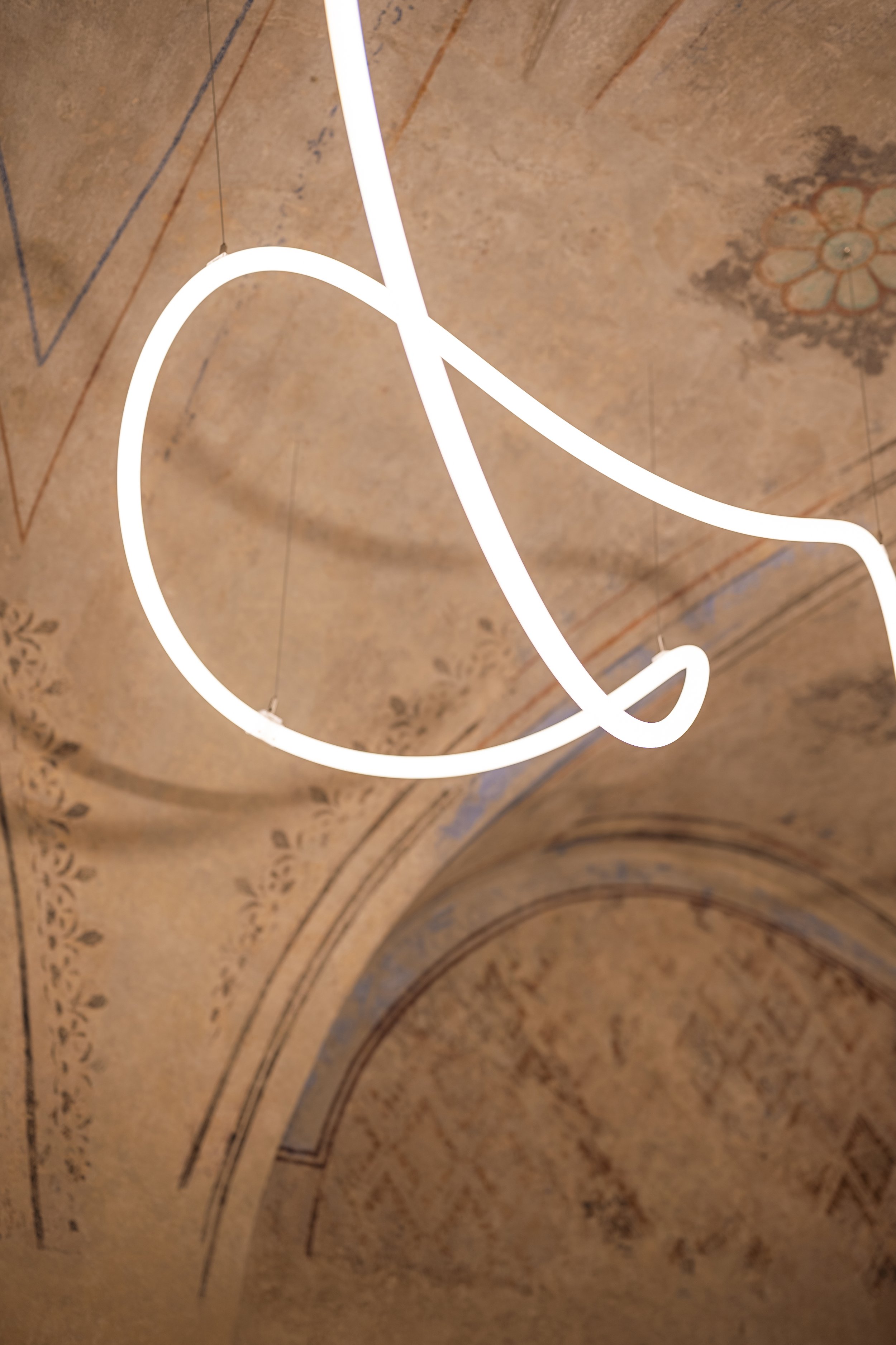 A light fixture winding beneath the restored stencil painting on the vault
