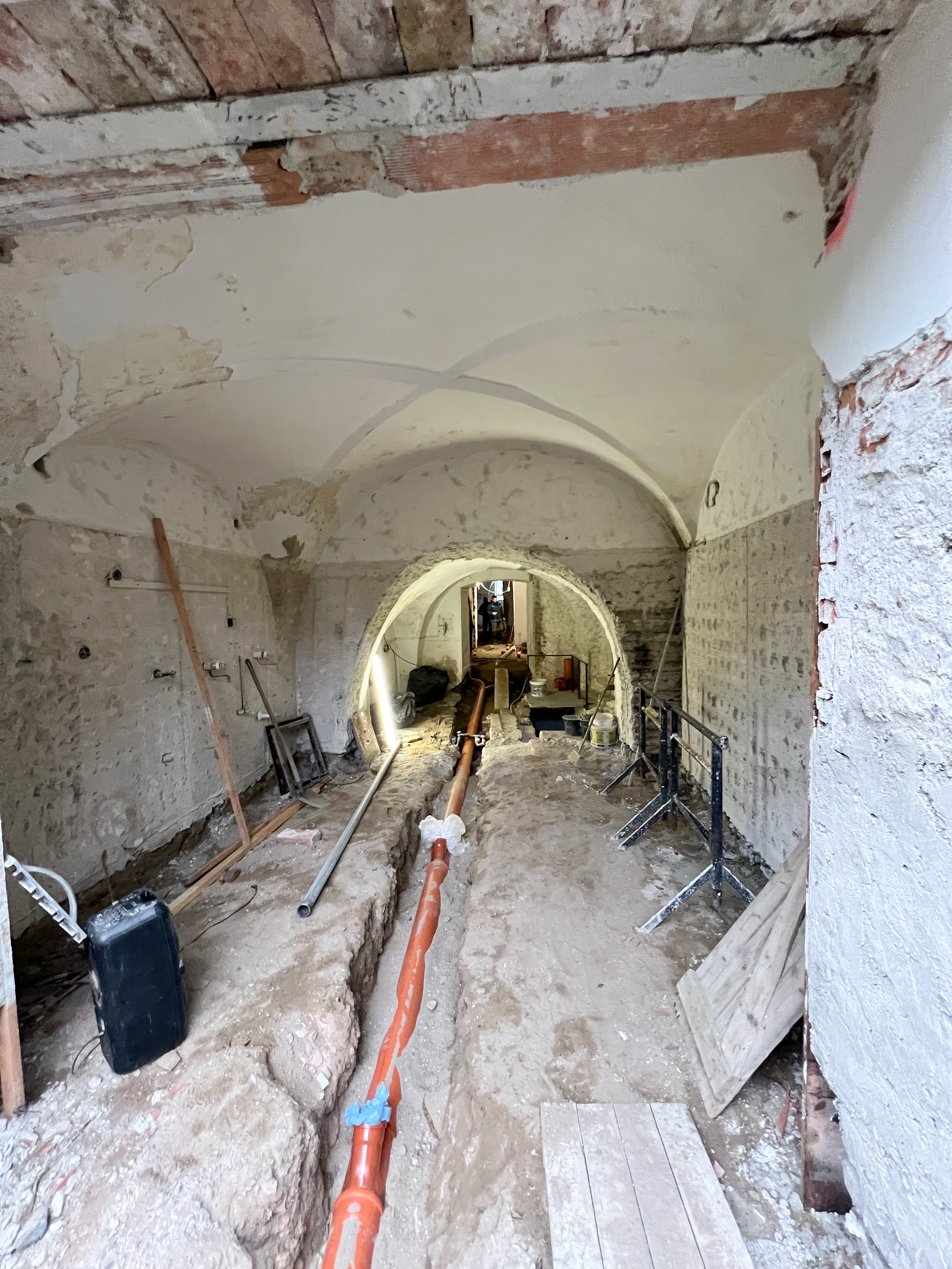 A vaulted hallway during construction, with utility lines in the open floor