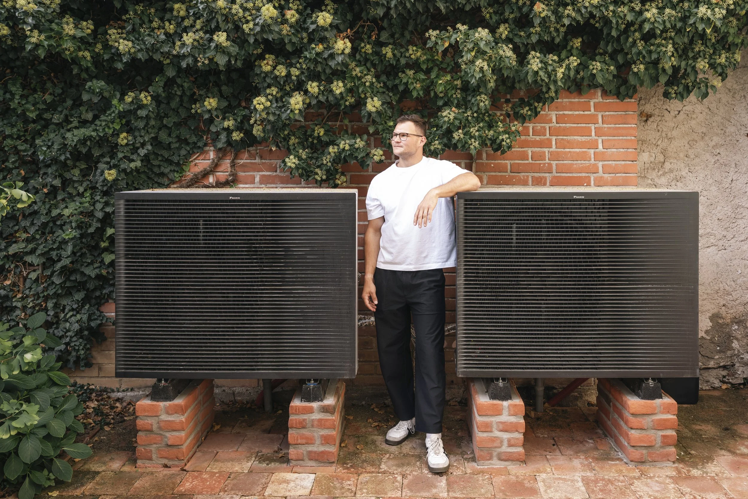 An architect in the courtyard of a house near outdoor heat pump units