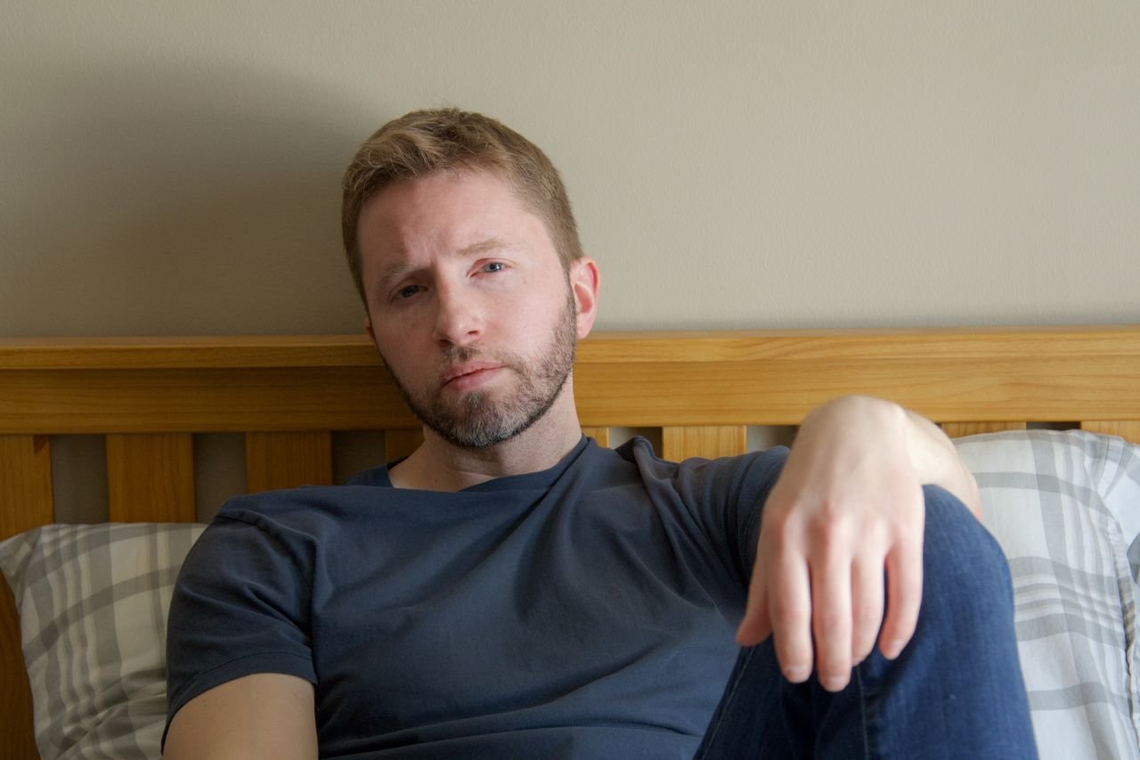 photo-of-a-sad-man-lying-in-bed