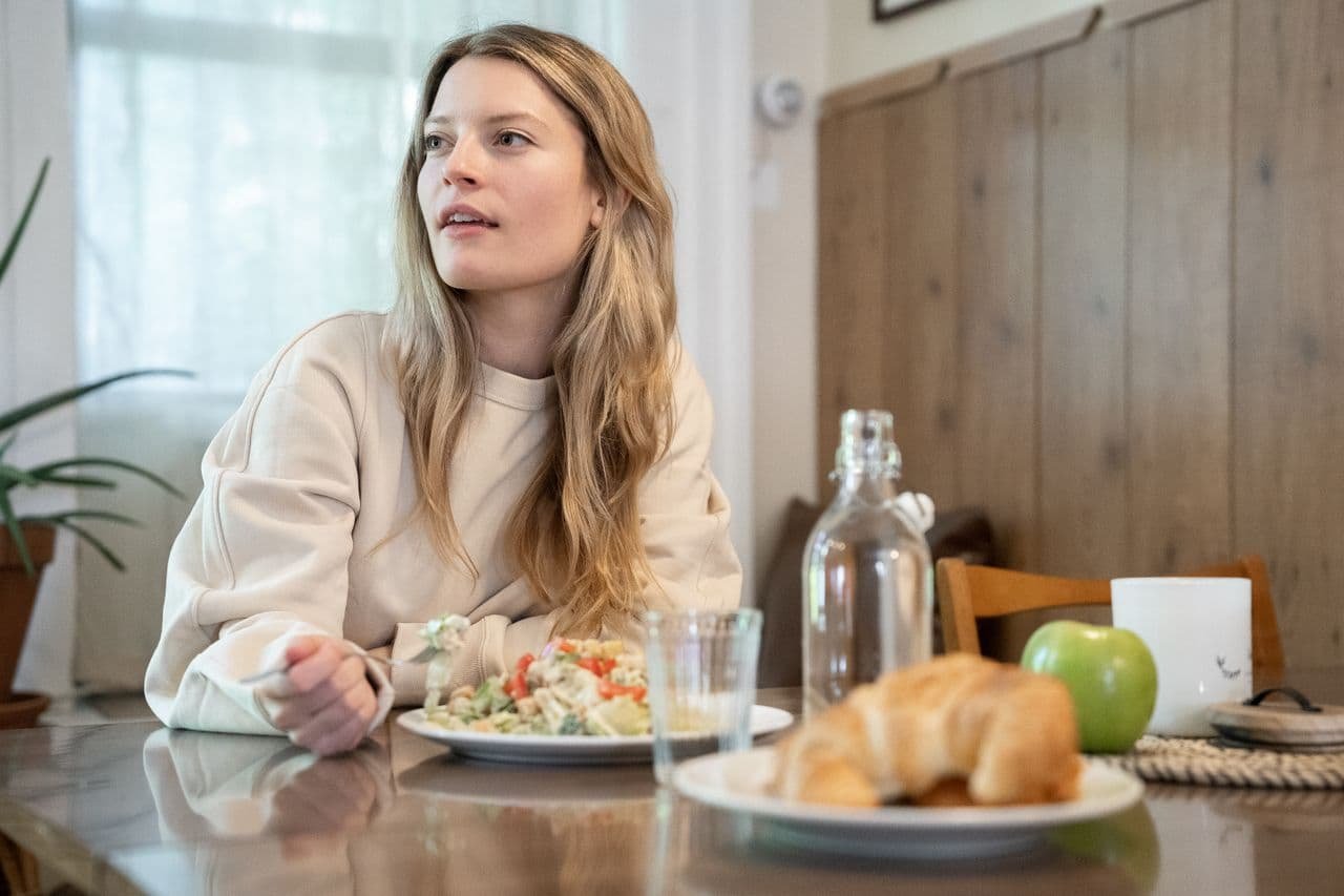 a-woman-in-beige-long-sleeve-shirt-eating-at-the-table
