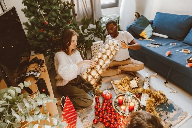 a-man-and-woman-sitting-on-the-floor-while-preparing-christmas-decorations