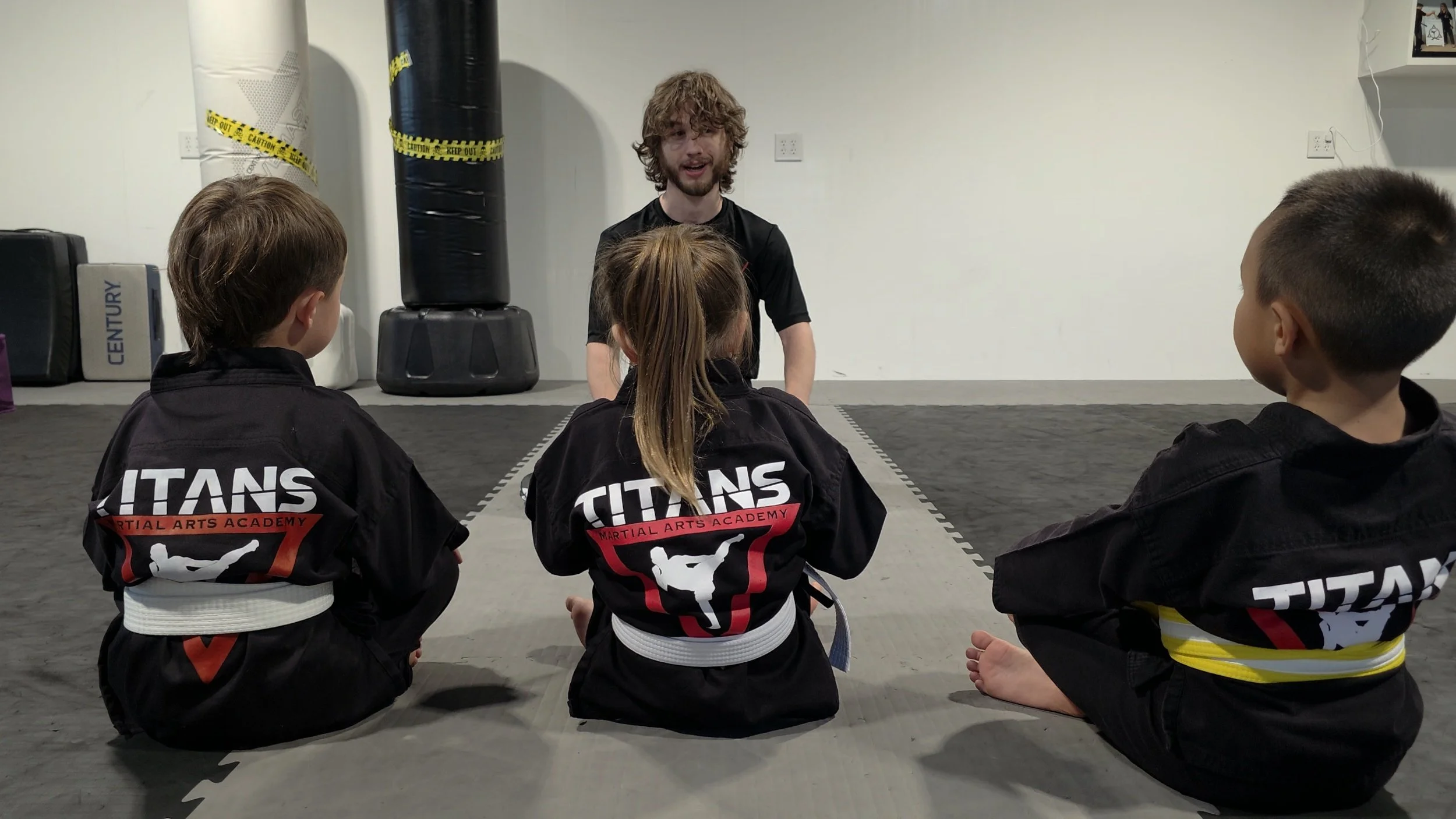 Martial arts instructor teaching three children in uniforms at a martial arts academy