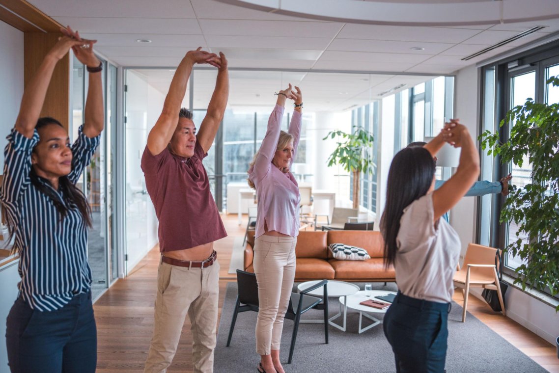 Employees taking part in a workplace wellbeing workshop, practising gentle Fascial Maneuvers and body awareness exercises together in Sydney, Australia