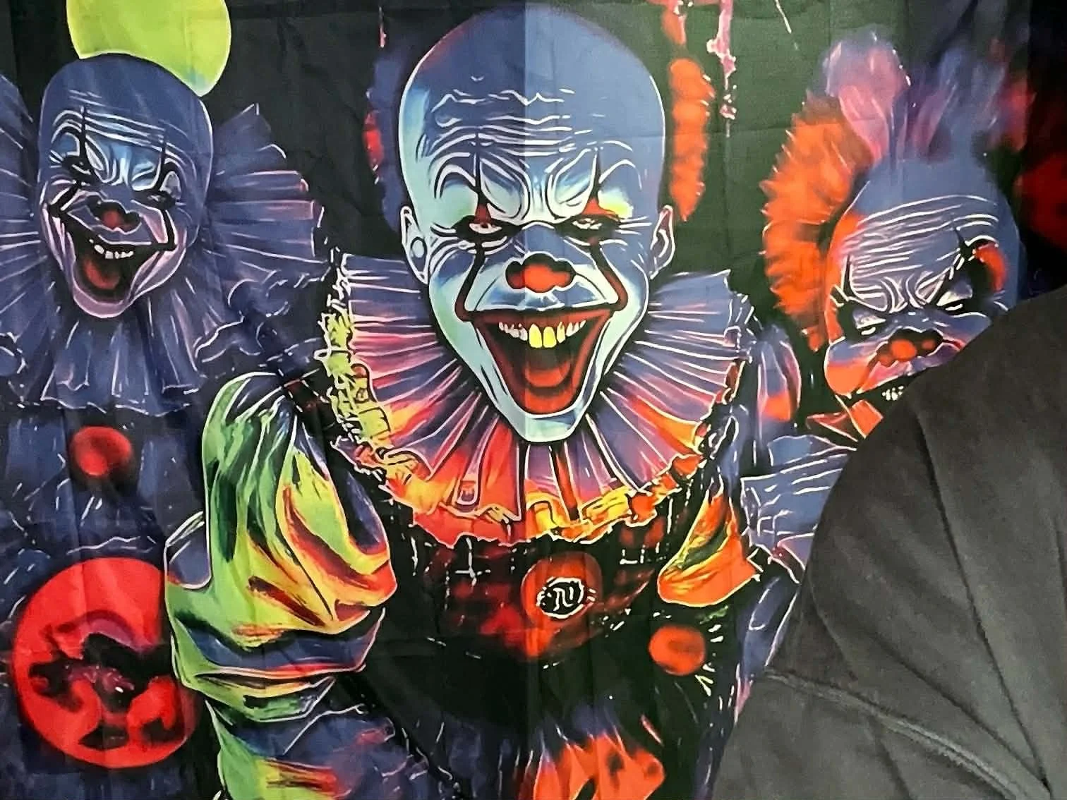 Colorful clown-themed artwork featuring multiple clown faces with exaggerated makeup and expressions, including a central clown with an open mouth and large yellow teeth, dressed in vibrant costumes.