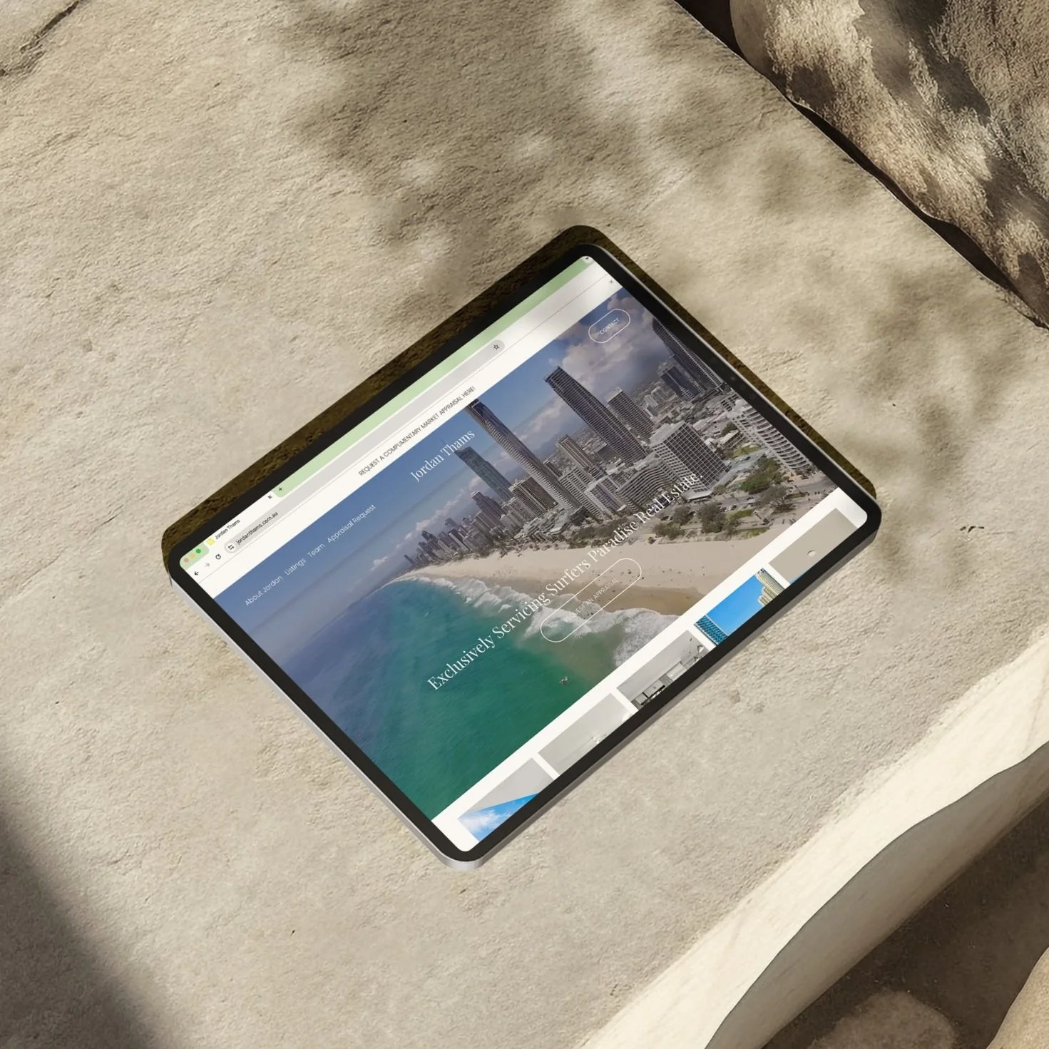 Tablet on beige surface displaying a webpage with a beach and cityscape image.