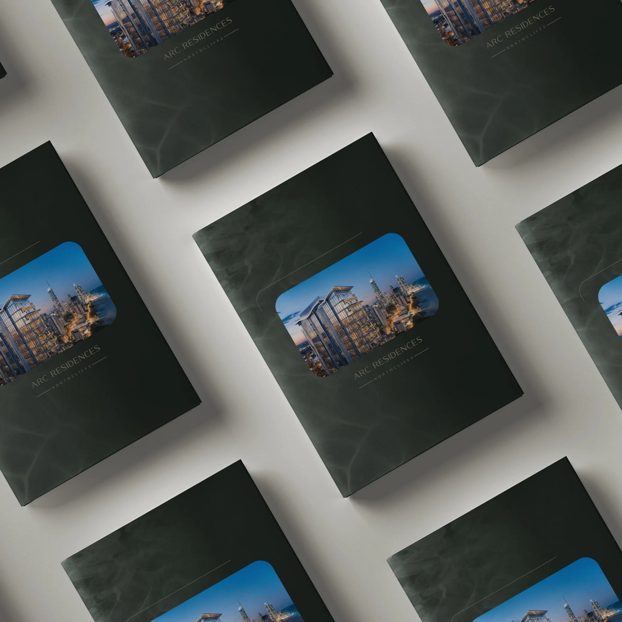 Brochures of ARC Residences laid out on a table, featuring a photo of modern skyscrapers on the cover.
