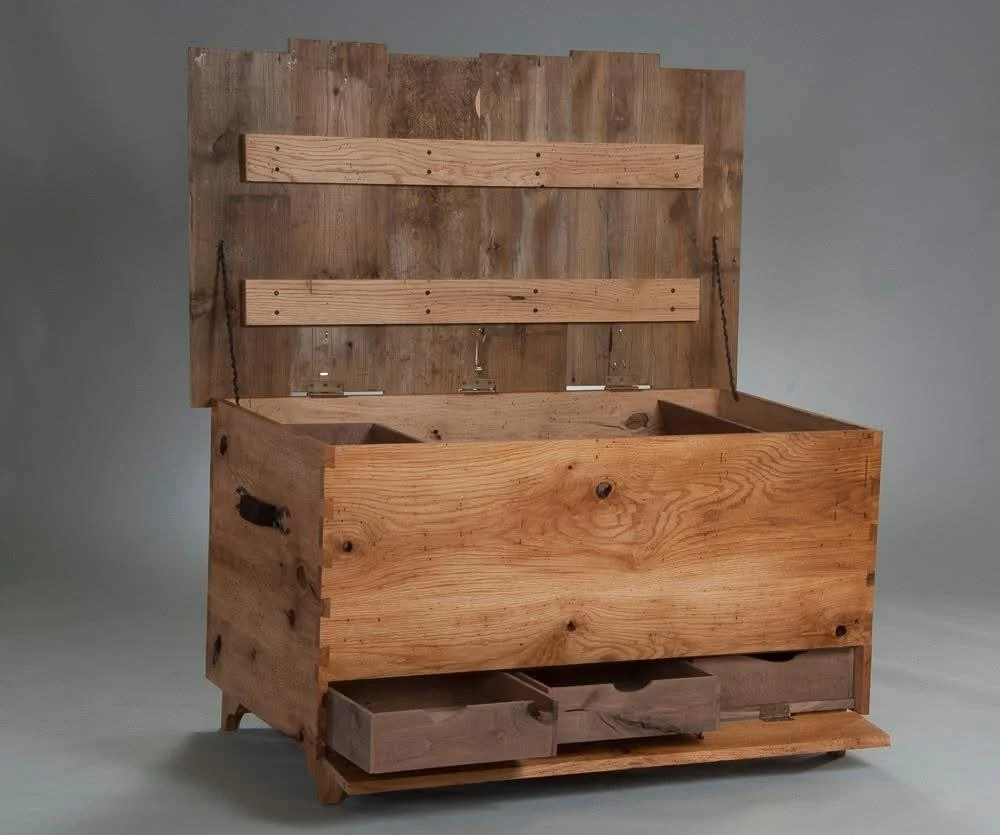 A rustic wooden hope chest with a hinged lid, open to show interior compartments, and featuring small drawers at the bottom.