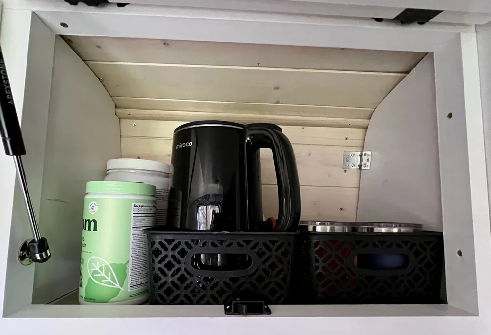  Upper cabinet used to store kettle, tea, coffee, and other beverages in van camper. 