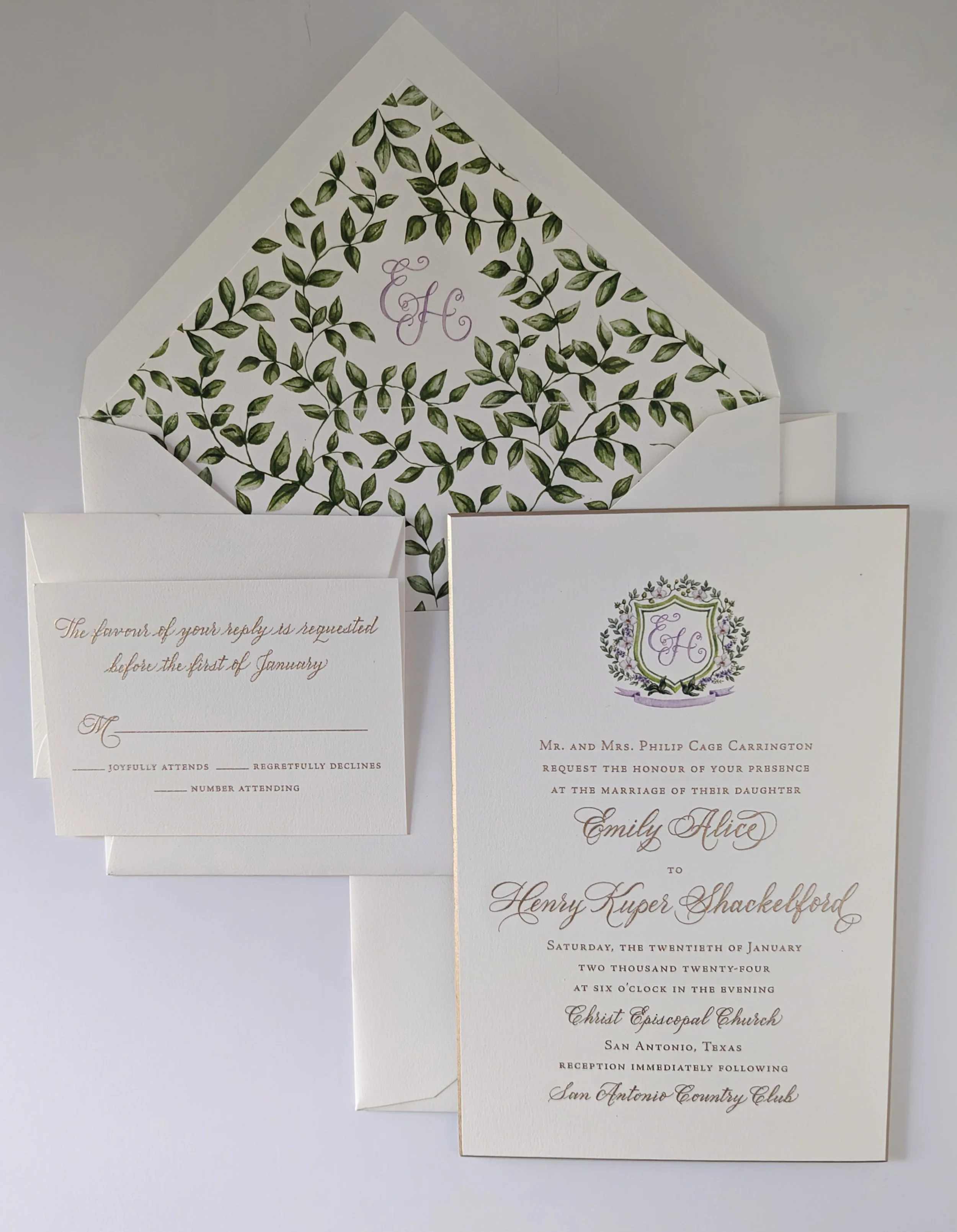 Wedding invitation suite with an envelope, RSVP card, and invitation card, featuring greenery and elegant script text.