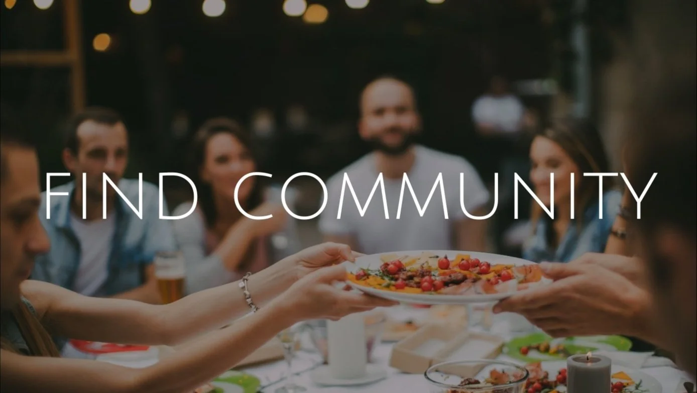 Group of people sharing a meal outdoors at night, with arms extending to exchange a dish, over a table of food, with the text 'Find Community' overlaid on the image.