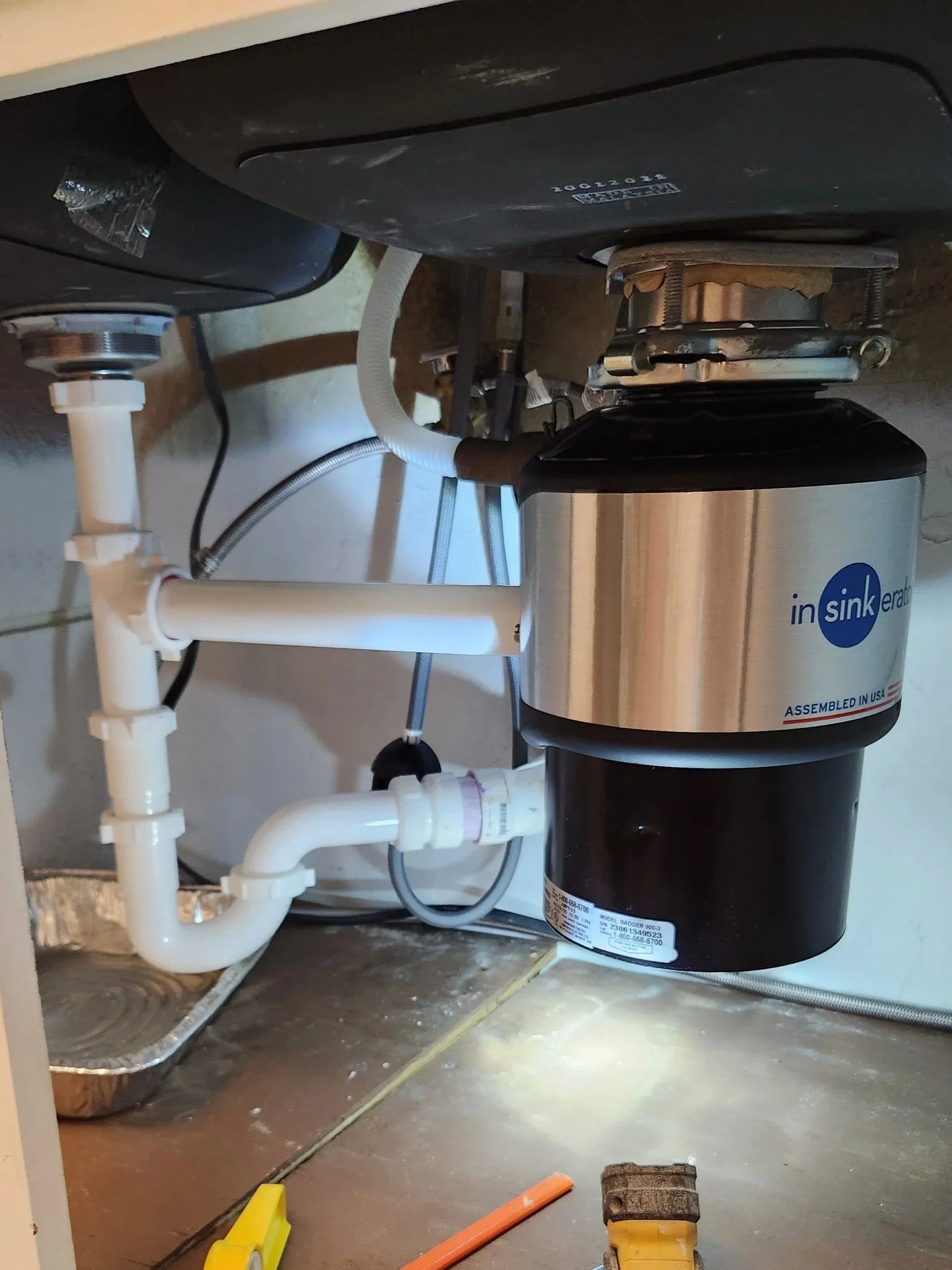 Newly installed garbage disposal under a kitchen sink by an Austin handyman