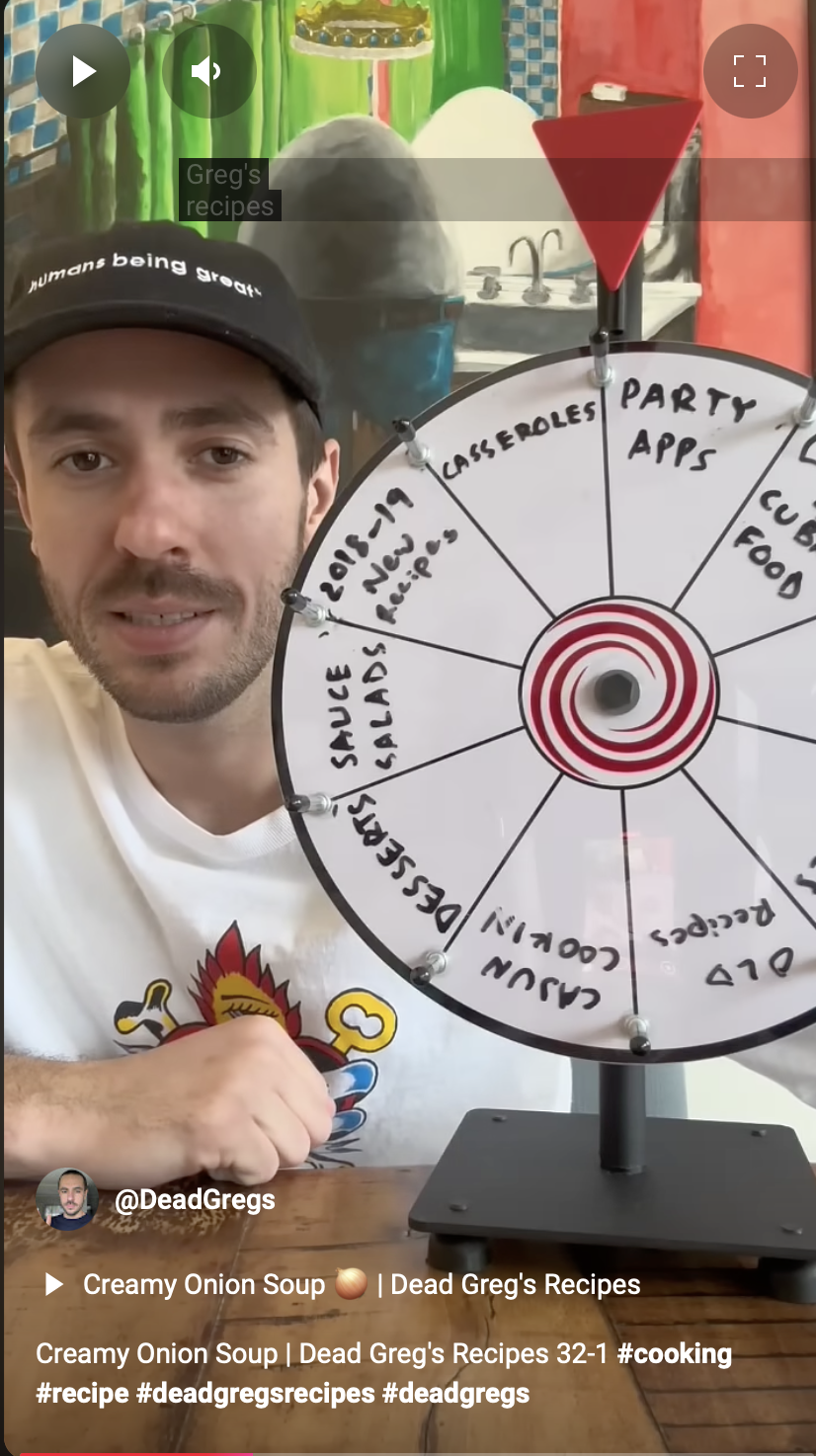 Person holding a spinning wheel with various food and recipe categories, in front of a colorful kitchen background.