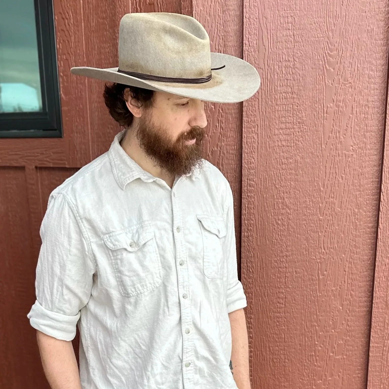 Man standing in front of a window wearing a Gus shaped hat
