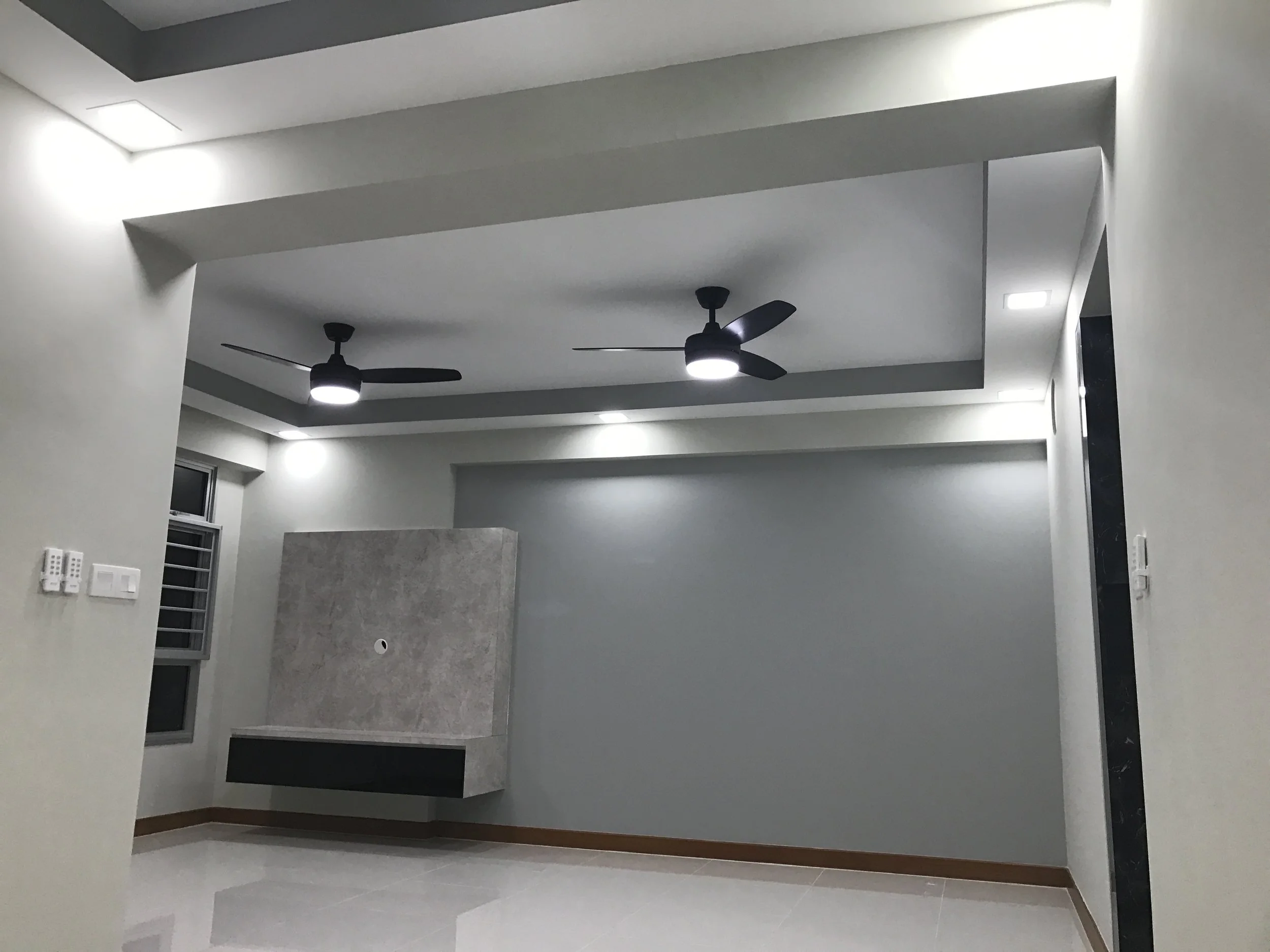 Empty modern room with white walls, gray ceiling, ceiling fans, and recessed lighting.