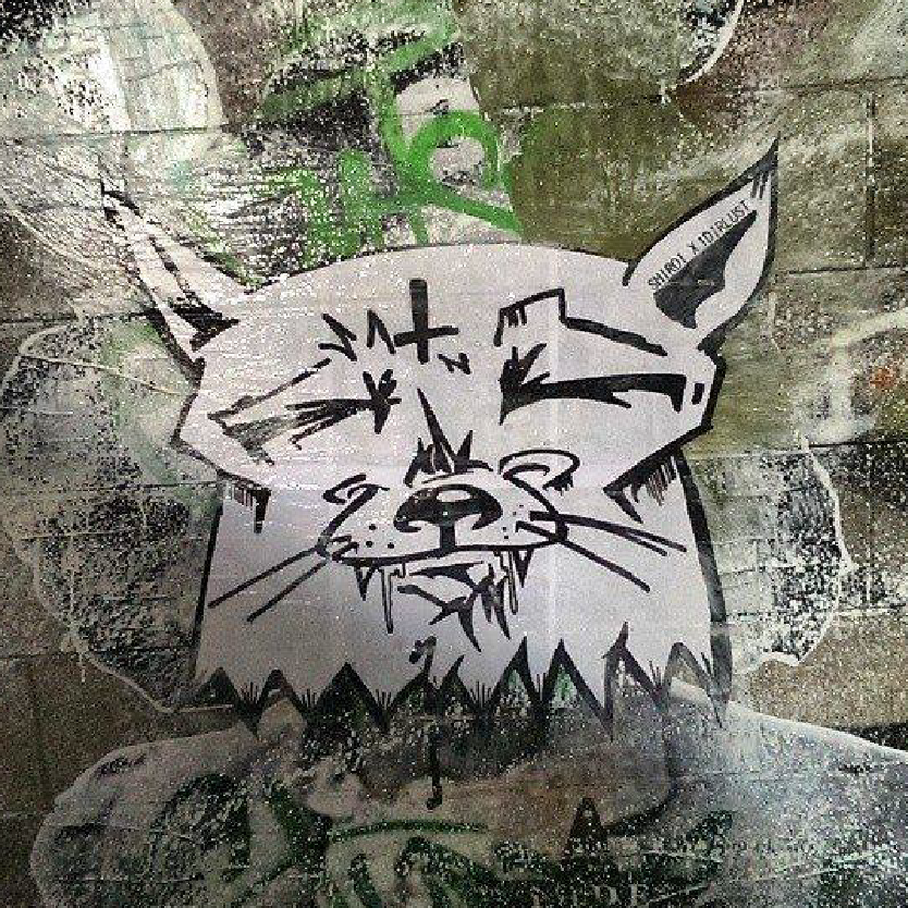 Graffiti of an abstract cat with sharp features on a textured wall.