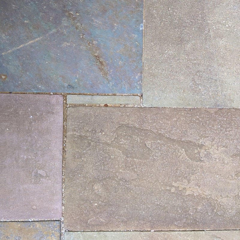 A close-up of four varied colors of bluestone and a thin little sliver of a different type in the middle fitted like a puzzle