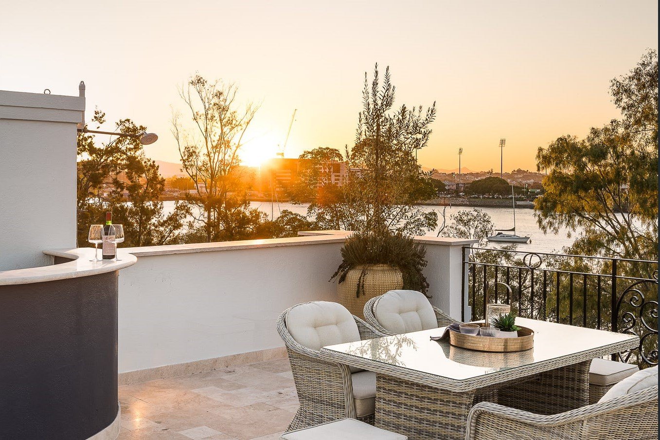 Sun setting over a styled outdoor rooftop dining area overlooking the Brisbane River.