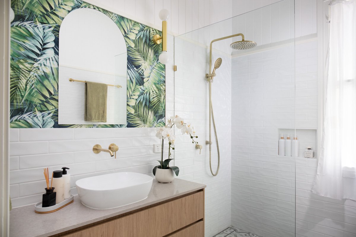Vanity sink and shower recess with gold tap wear and tropical wallpaper and arch mirror on the splashback. Interior design by Marilena Baynes, Brisbane.