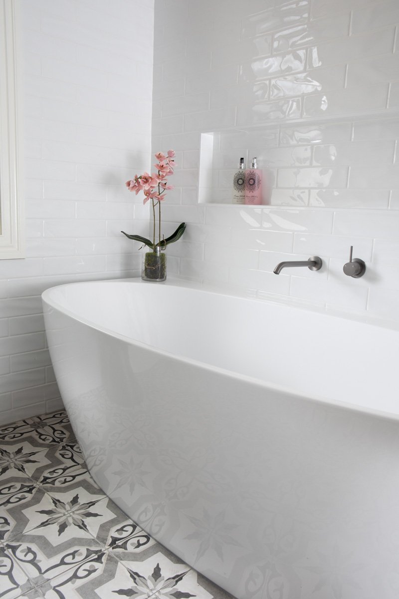Freestanding bathtub on black and white tiles in this Morningside interior design project by Marilena Baynes