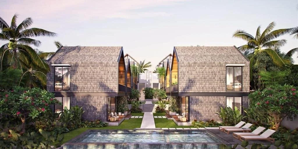 Two modern two-story houses with gabled roofs, large windows, surrounded by lush tropical vegetation, with a swimming pool in the foreground, set in a landscaped garden.