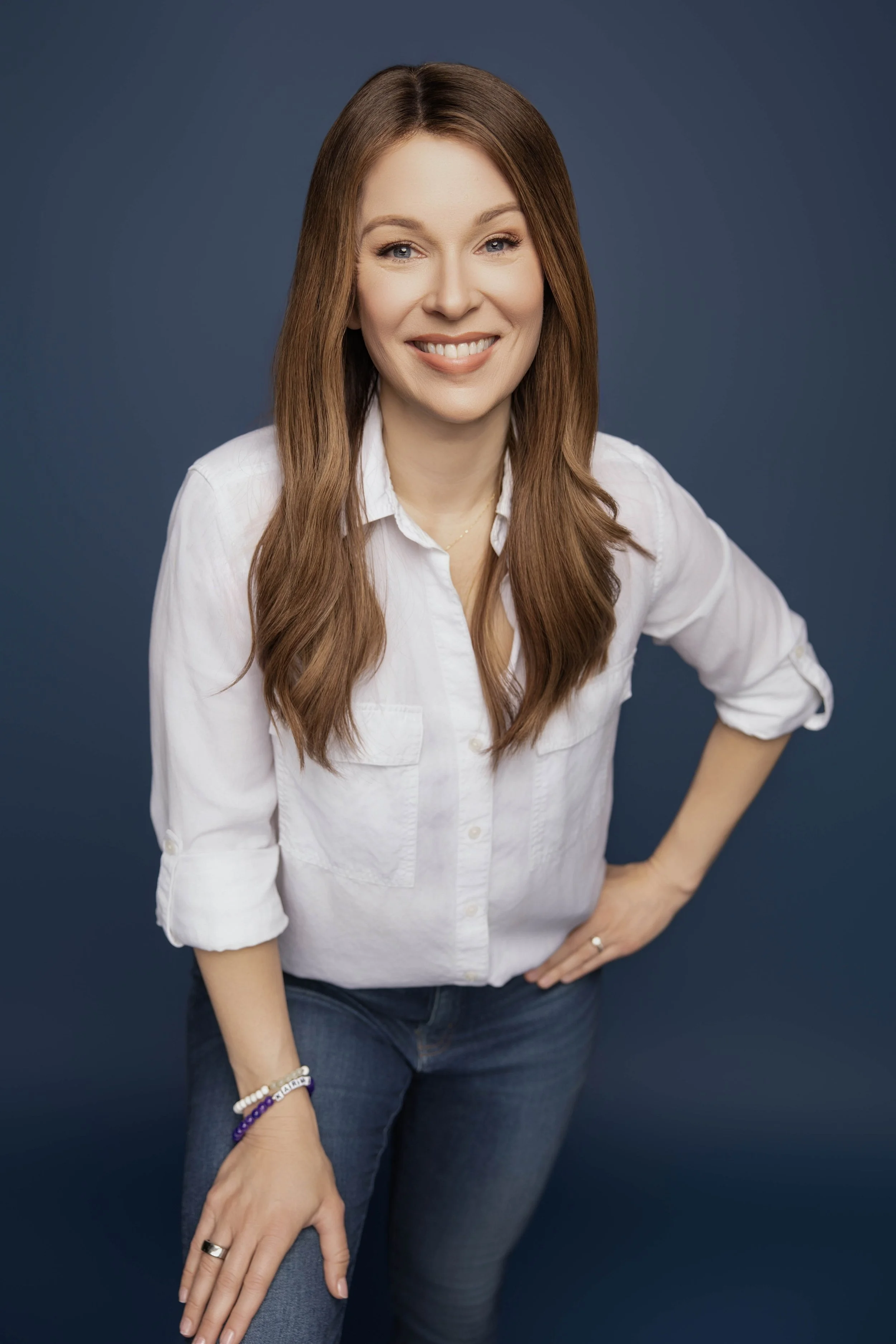 Woman smiling and looking at the camera wearing a white button up shirt