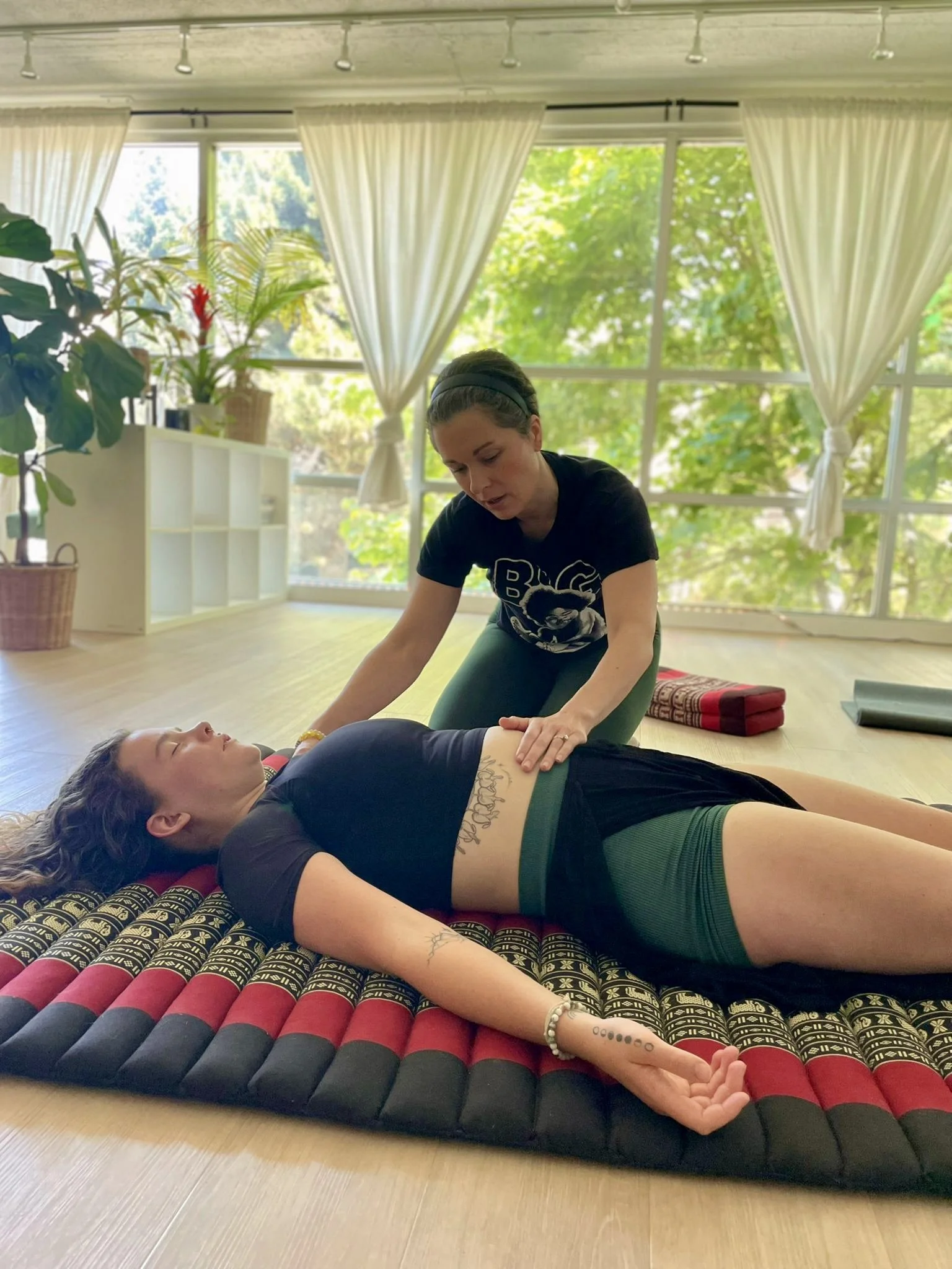 A woman with short hair performing breathwork on another woman lying on the ground