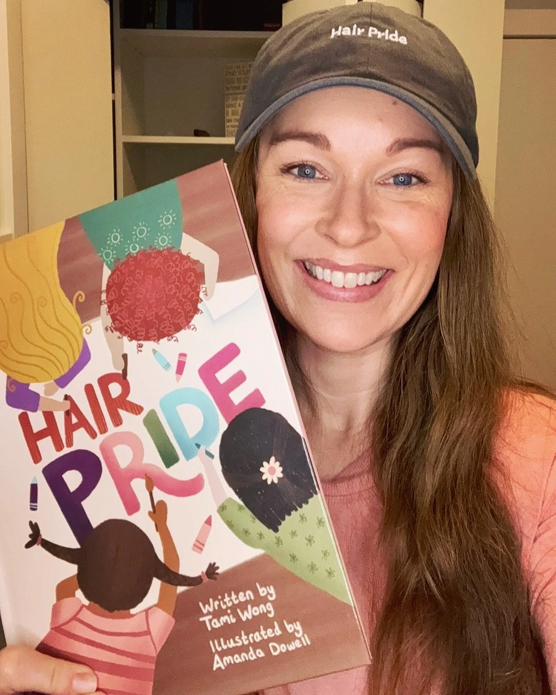 Tami Wong holding her children's book, Hair Pride, which was inspired by her own experience with hair loss starting at fifteen