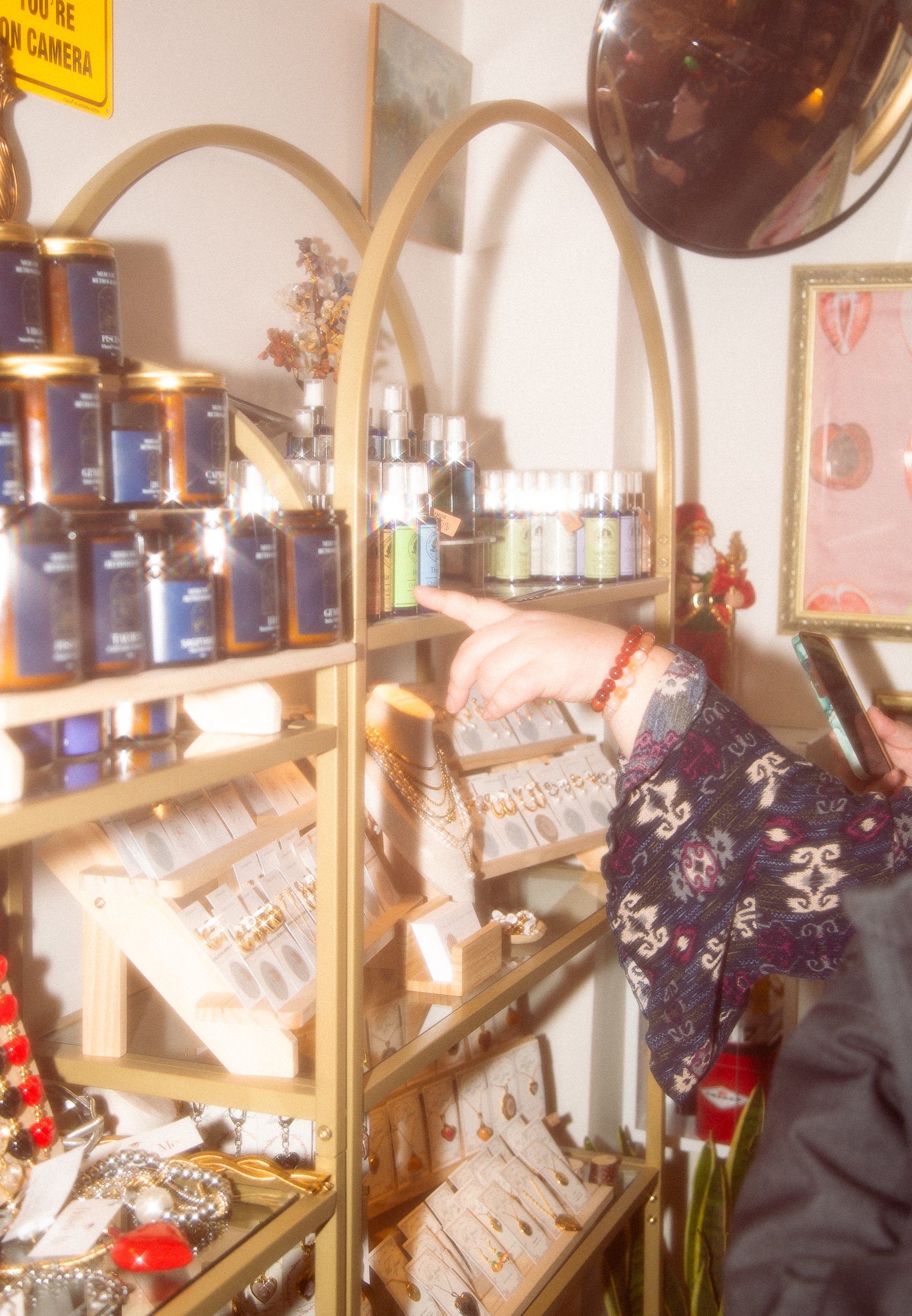 Person browsing jewelry and aromatherapy products on display shelves at a store.