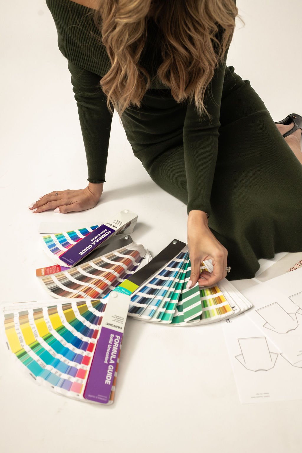 Apparel brand consultant Natalia reviewing Pantone color guides and garment patterns during a product development session