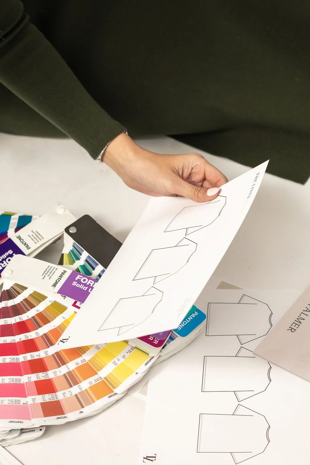 Apparel tech packs and Pantone color guides used in product development for client brands at The Lines by Natalia