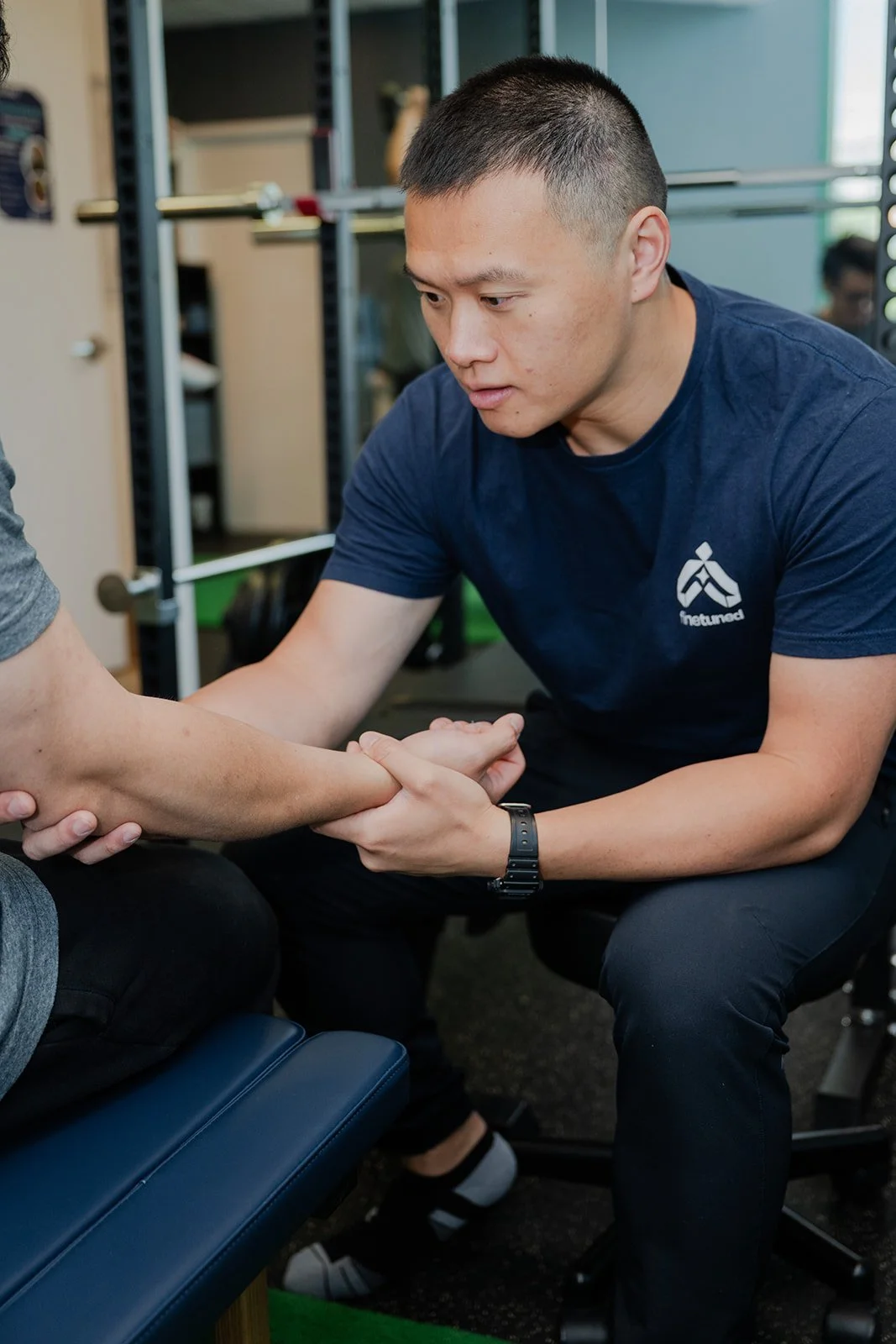 A patient holding a dumbbell doing rehab exercises for tennis elbow, or elbow pain, while another a chiropractor helps support their arm.