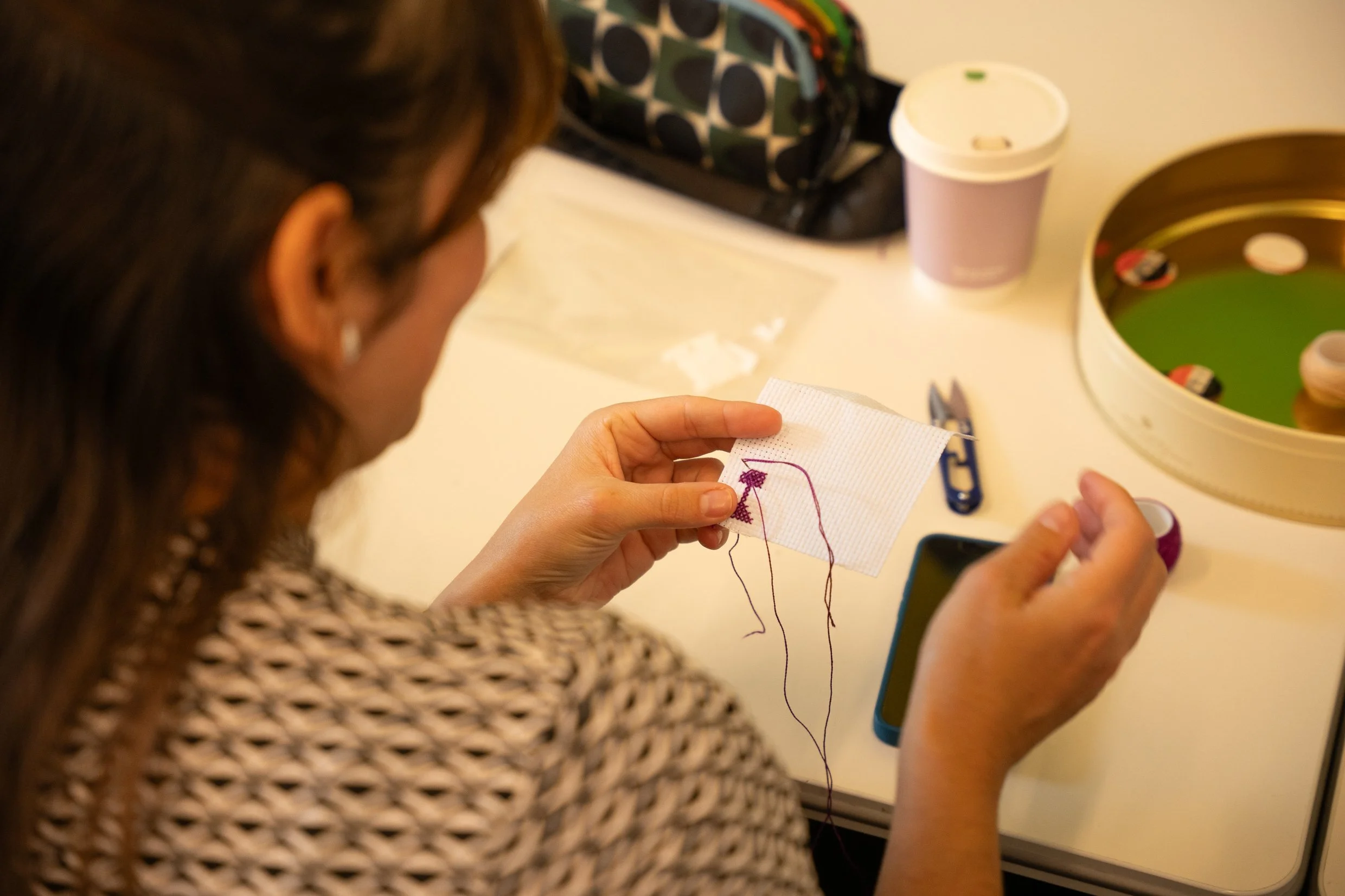 Participant learning traditional Palestinian tatreez cross-stitch embroidery on Aida fabric during a workshop with The Tatreez Collective.