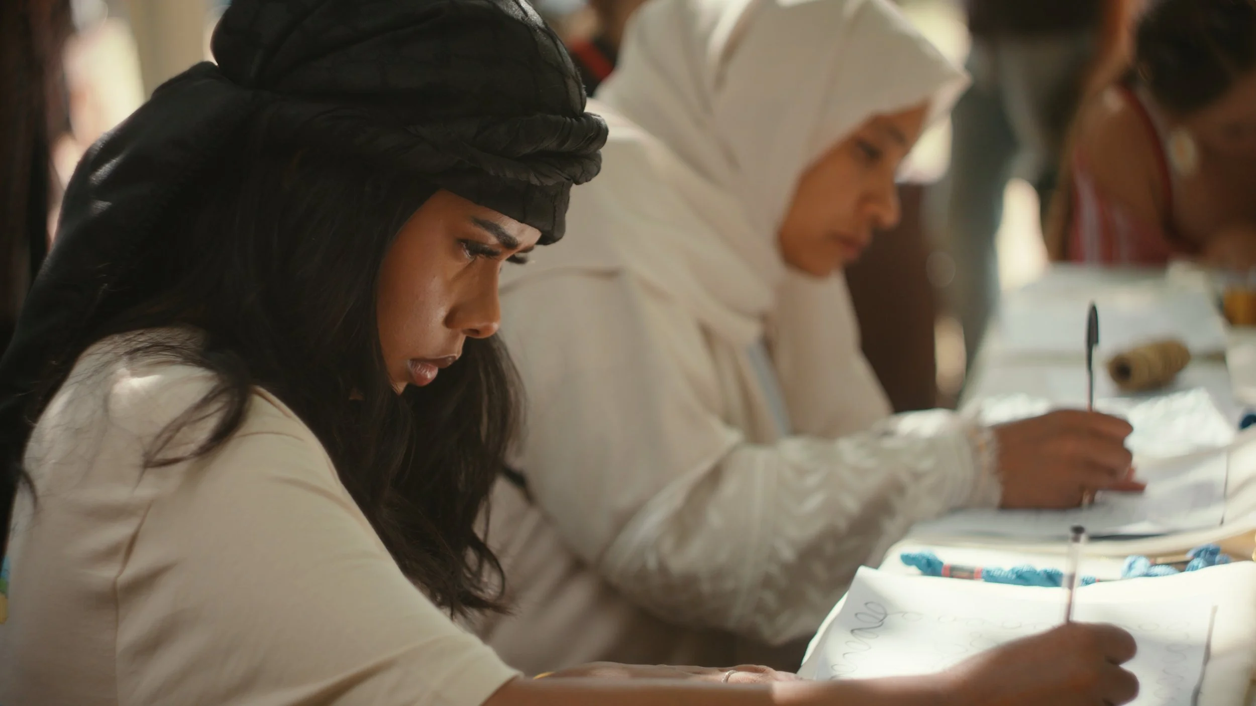 Two participants tracing embroidery patterns during a Palestinian embroidery workshop organised by The Tatreez Collective.
