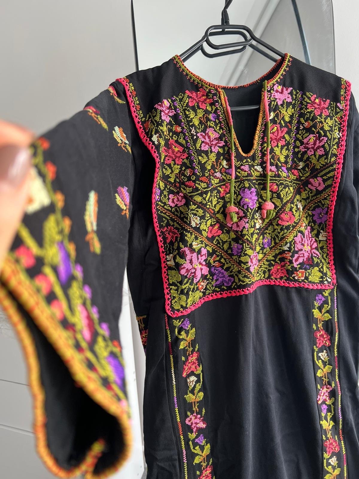 Refurbished black Palestinian thobe with colourful floral embroidery in pink, purple and green across the bodice and sleeves.