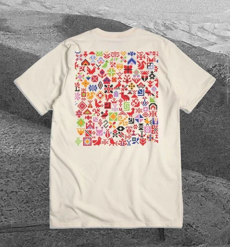 White Ben Howard tour T-shirt featuring a colourful design of cross-stitch-inspired motifs, created in collaboration with The Tatreez Collective.
