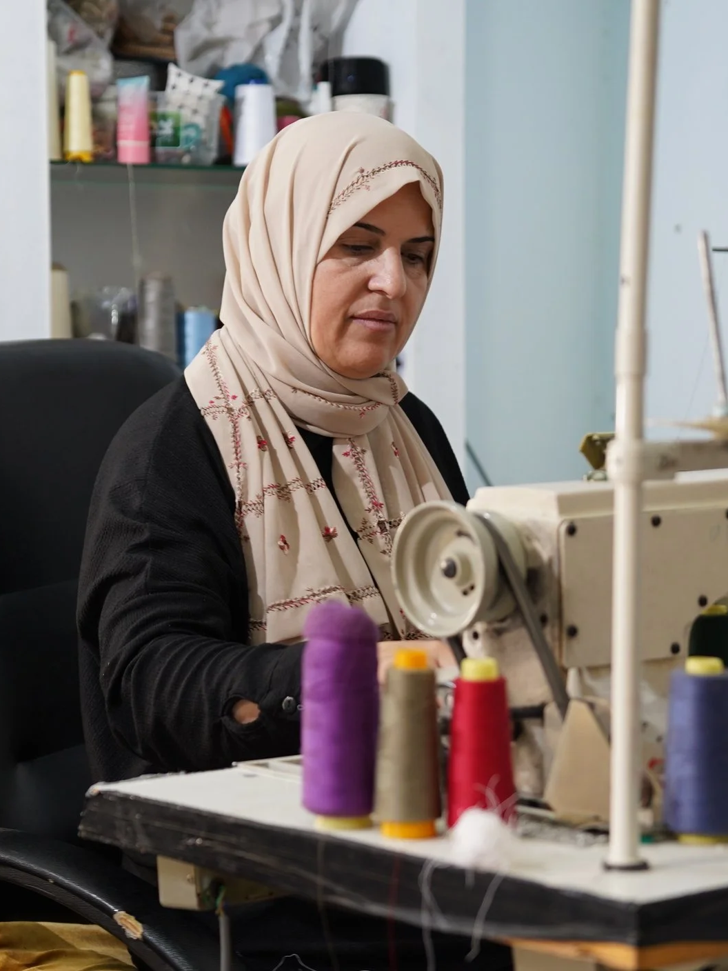 Palestinian artisan working at a sewing machine in The Tatreez Collective's clothing cooperative in Beit Liqya, Palestine.