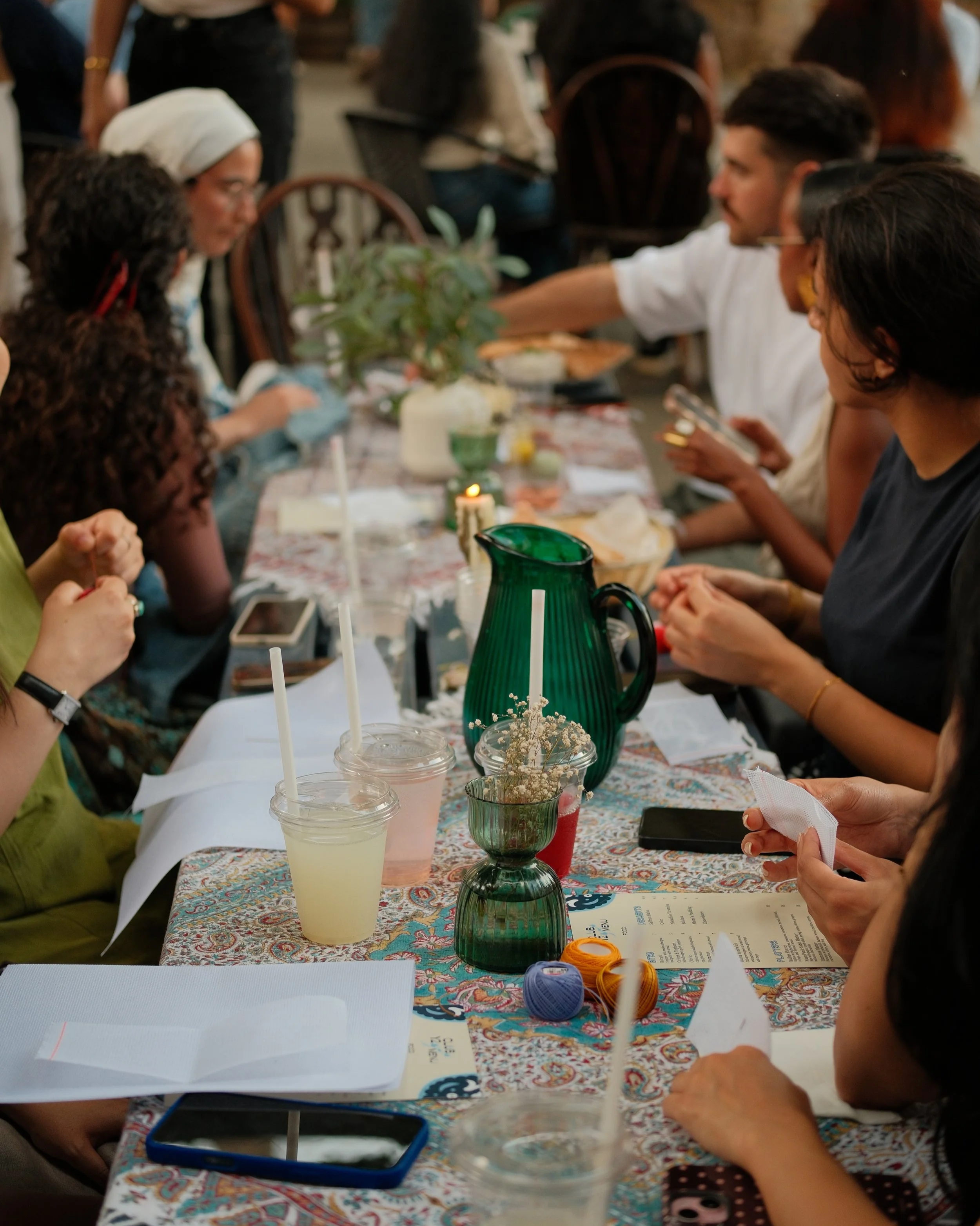 A mixed group of participants gathered around a table for a Palestinian embroidery workshop with The Tatreez Collective