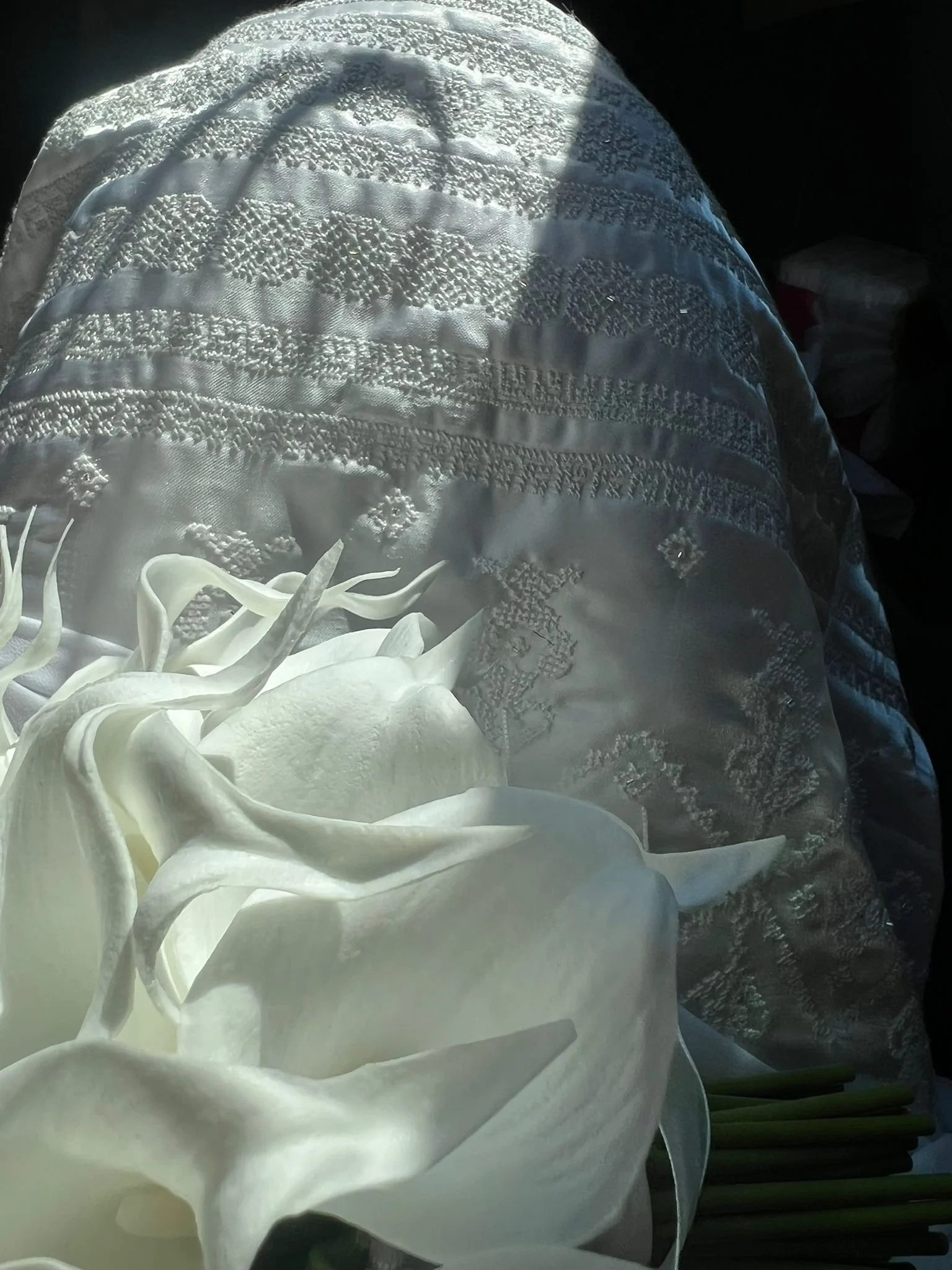 Close-up of a bespoke bridal dress featuring intricate hand embroidery in white, gold and silver threads.