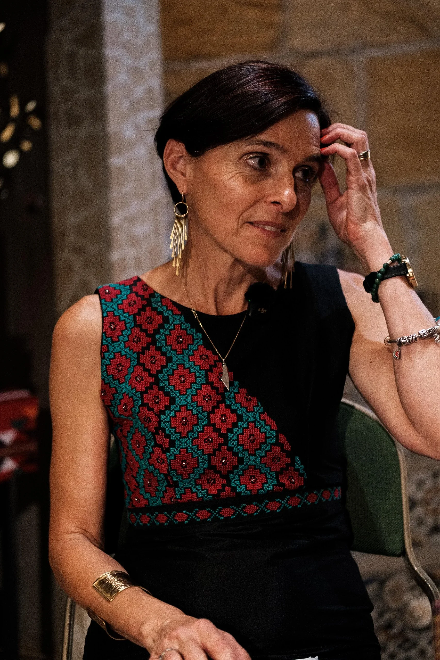 Woman wearing a bespoke black sleeveless garment with red and turquoise Palestinian tatreez embroidery by The Tatreez Collective.